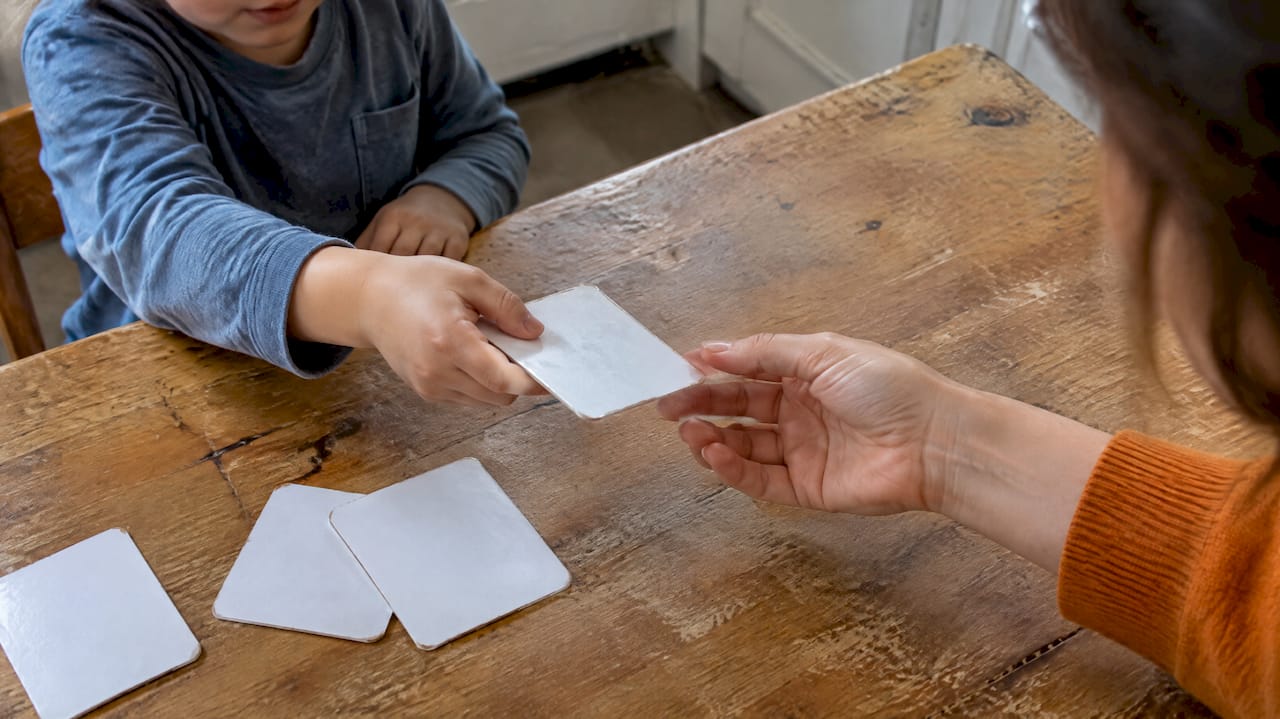 Child handing picture card to caregiver
