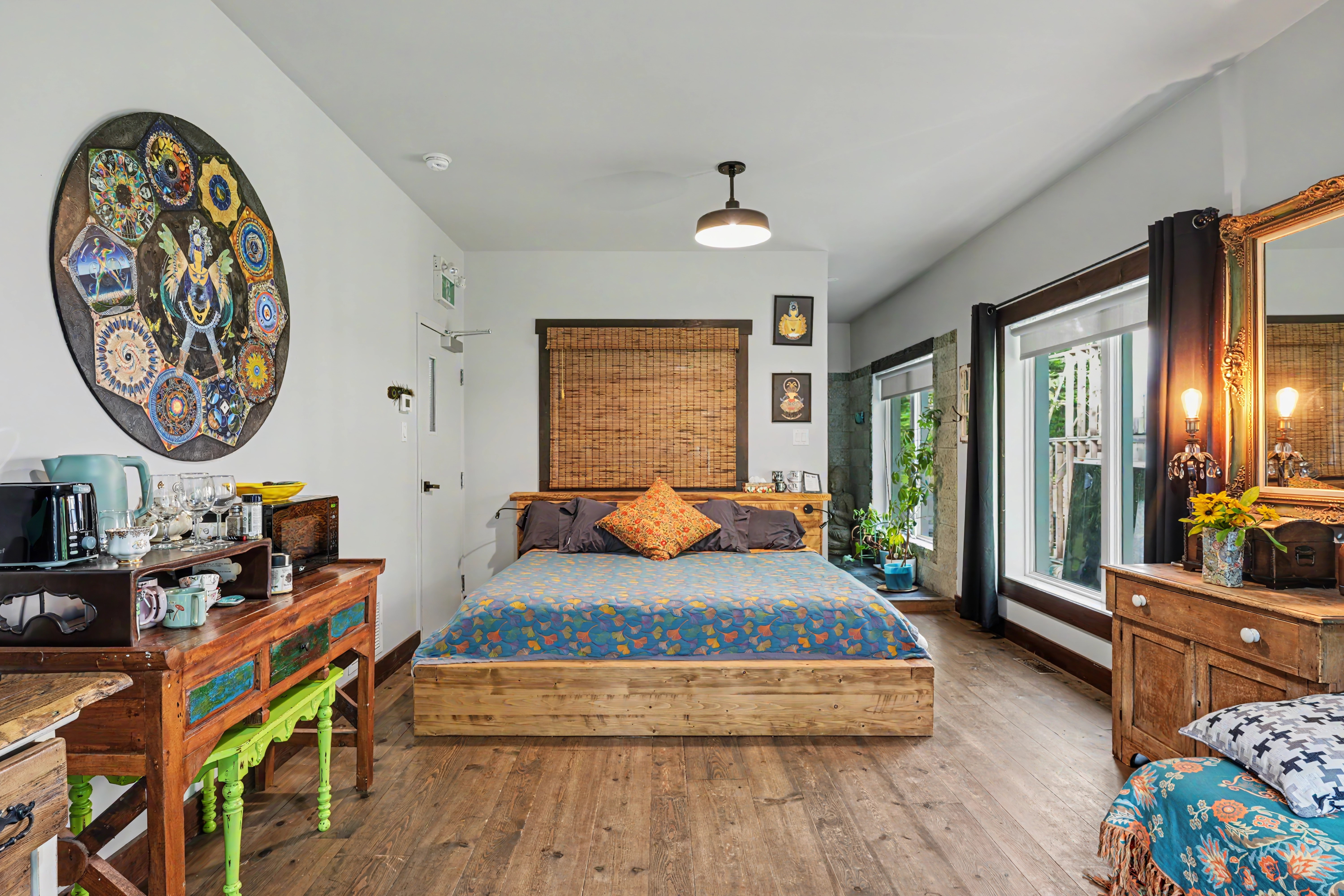 Lit en bois, déco inspirée de l’Asie et plancher de bois naturel, grandes fenêtres lumineuses.