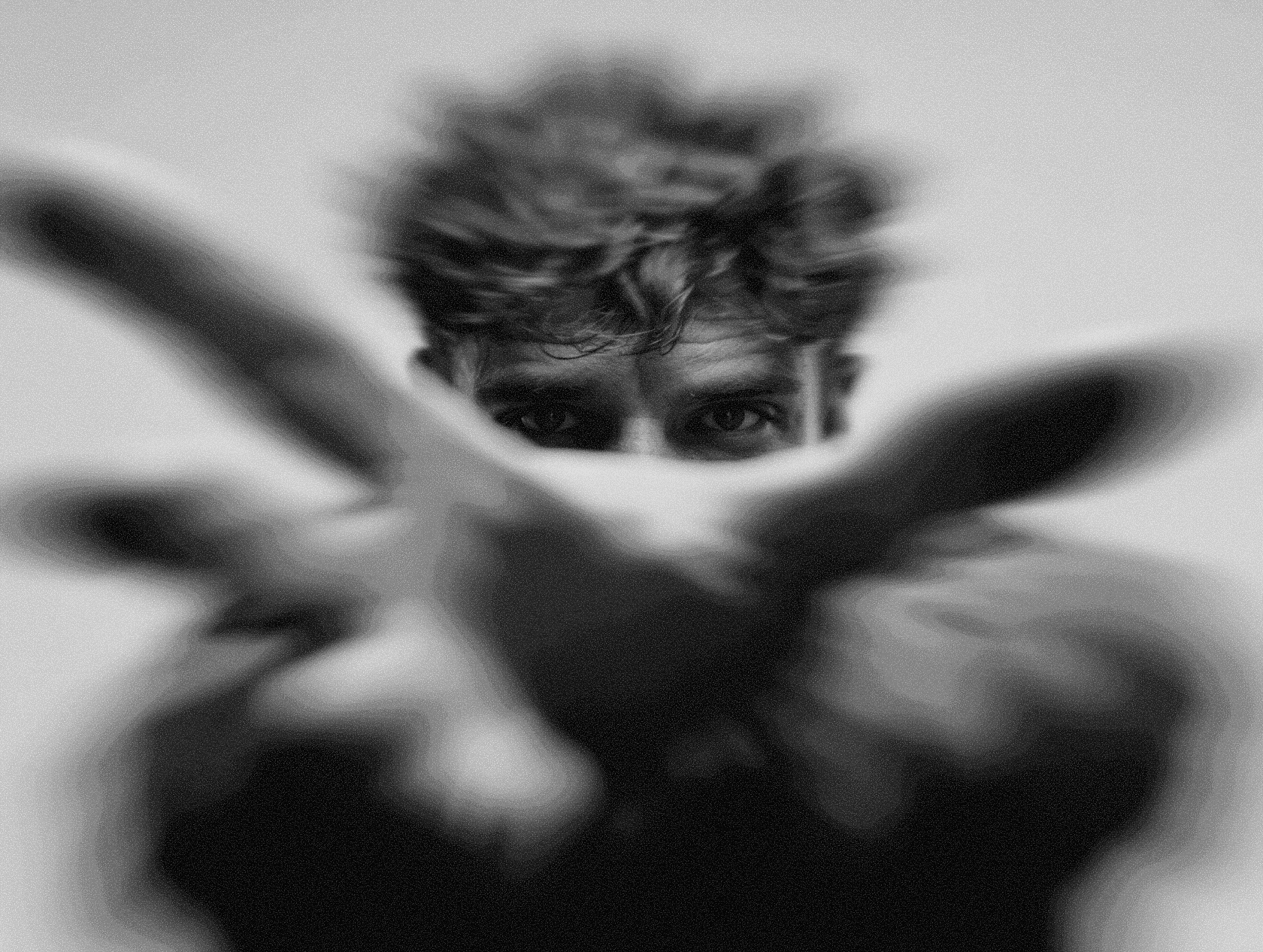 A face partially hidden behind hands with rough textured details and contrast