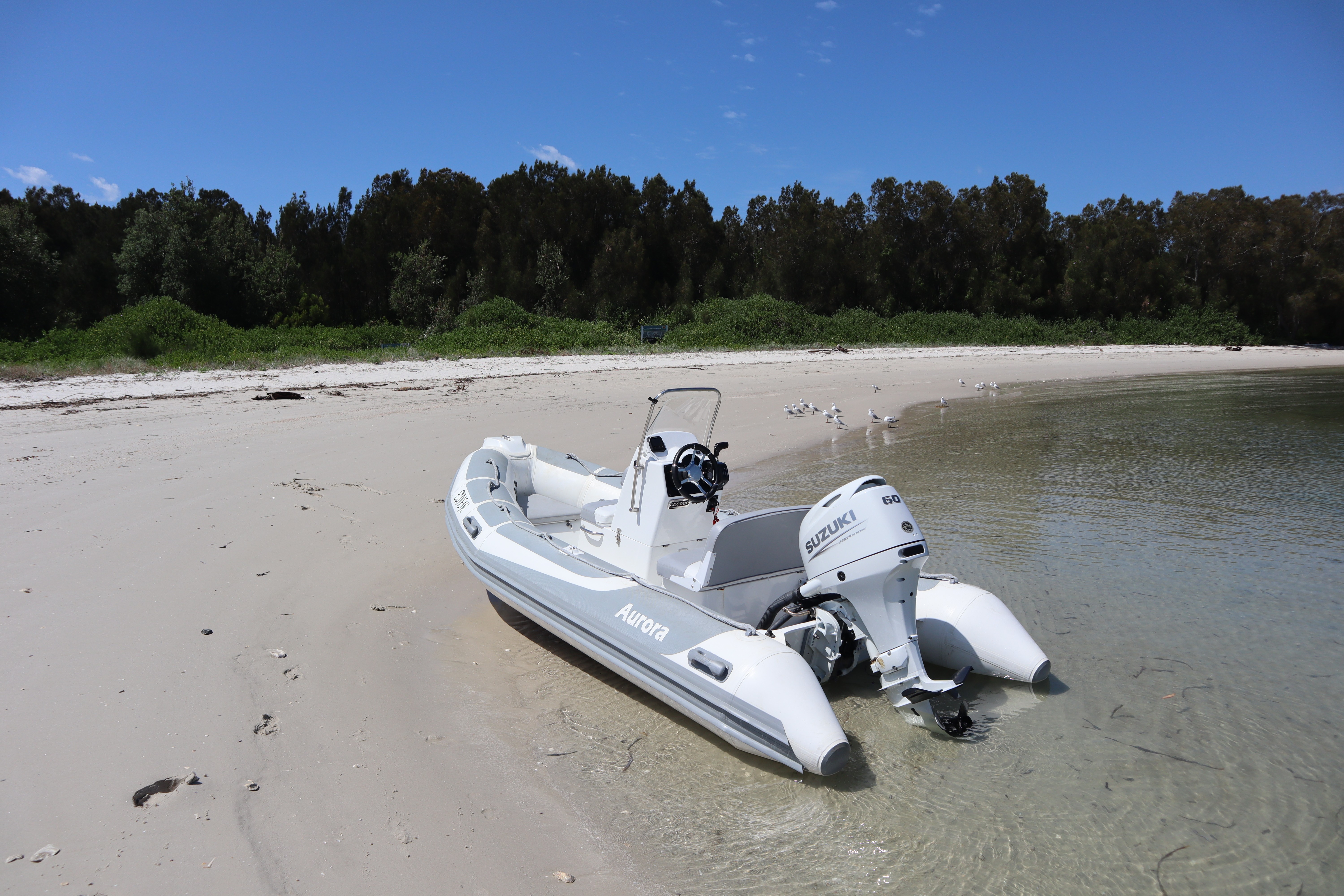 A winding road cuts through rocky terrain, surrounded by patches of green grass and illuminated by sunlight.