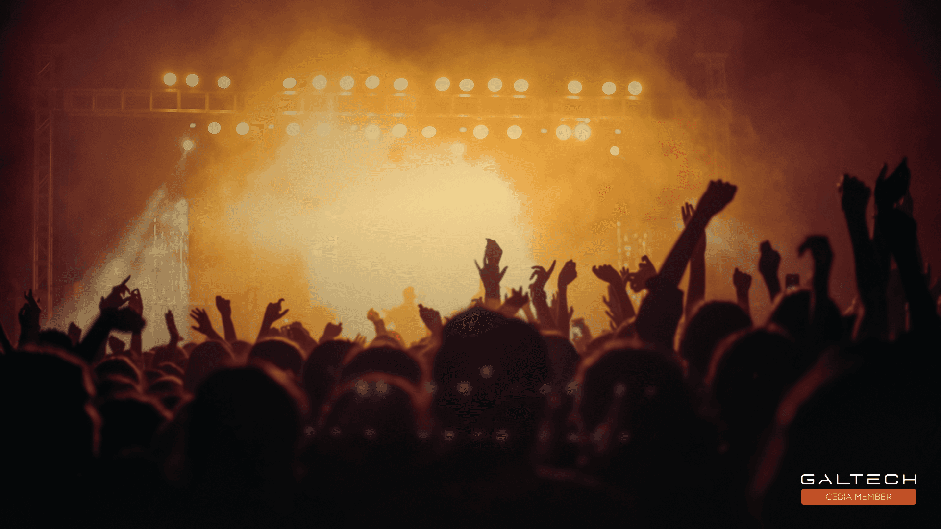 Crowd with hands up at a concert with stage lights