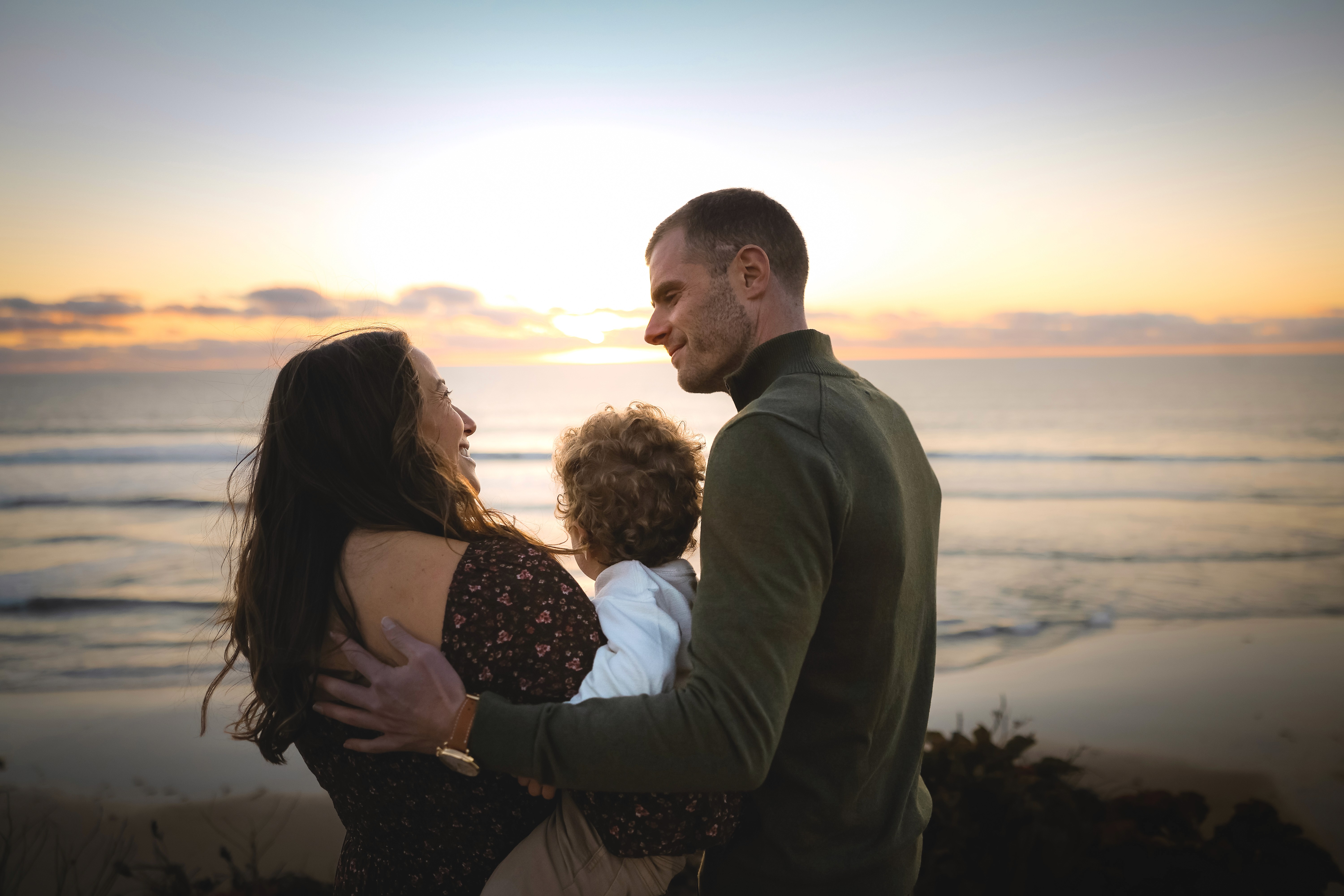 Family playing together at the cliffside during a sunset maternity session.
