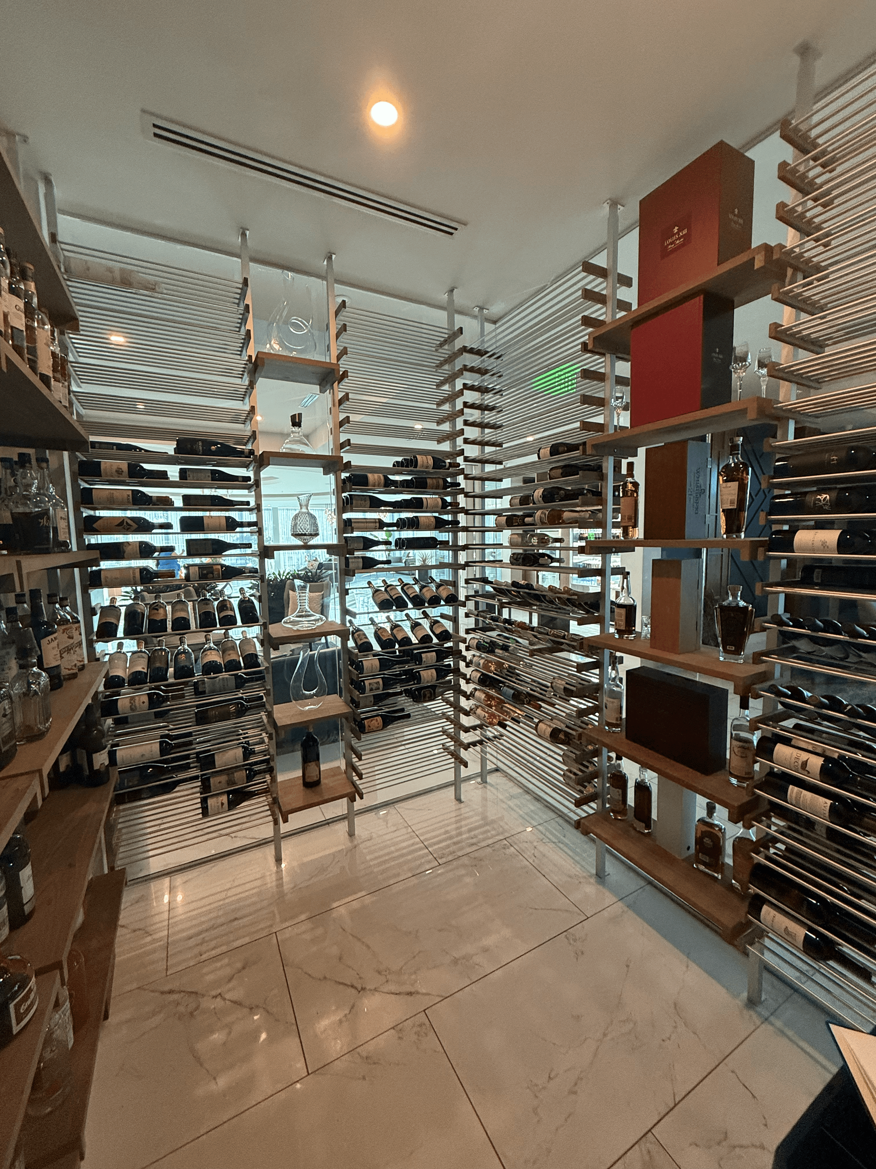 Central perspective inside the Cambria Waco Hotel wine cellar showcasing precision-aligned aluminum and walnut wine racking with a balanced, symmetrical display of the hotel’s wine collection.
