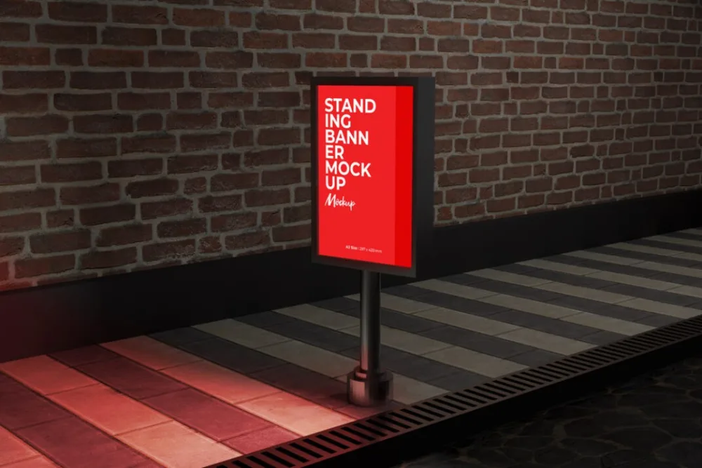 Standing banner mockup in an urban setting, positioned on a tiled walkway with a brick wall backdrop. The bold red banner is illuminated by moody, ambient lighting, creating a modern, industrial vibe.