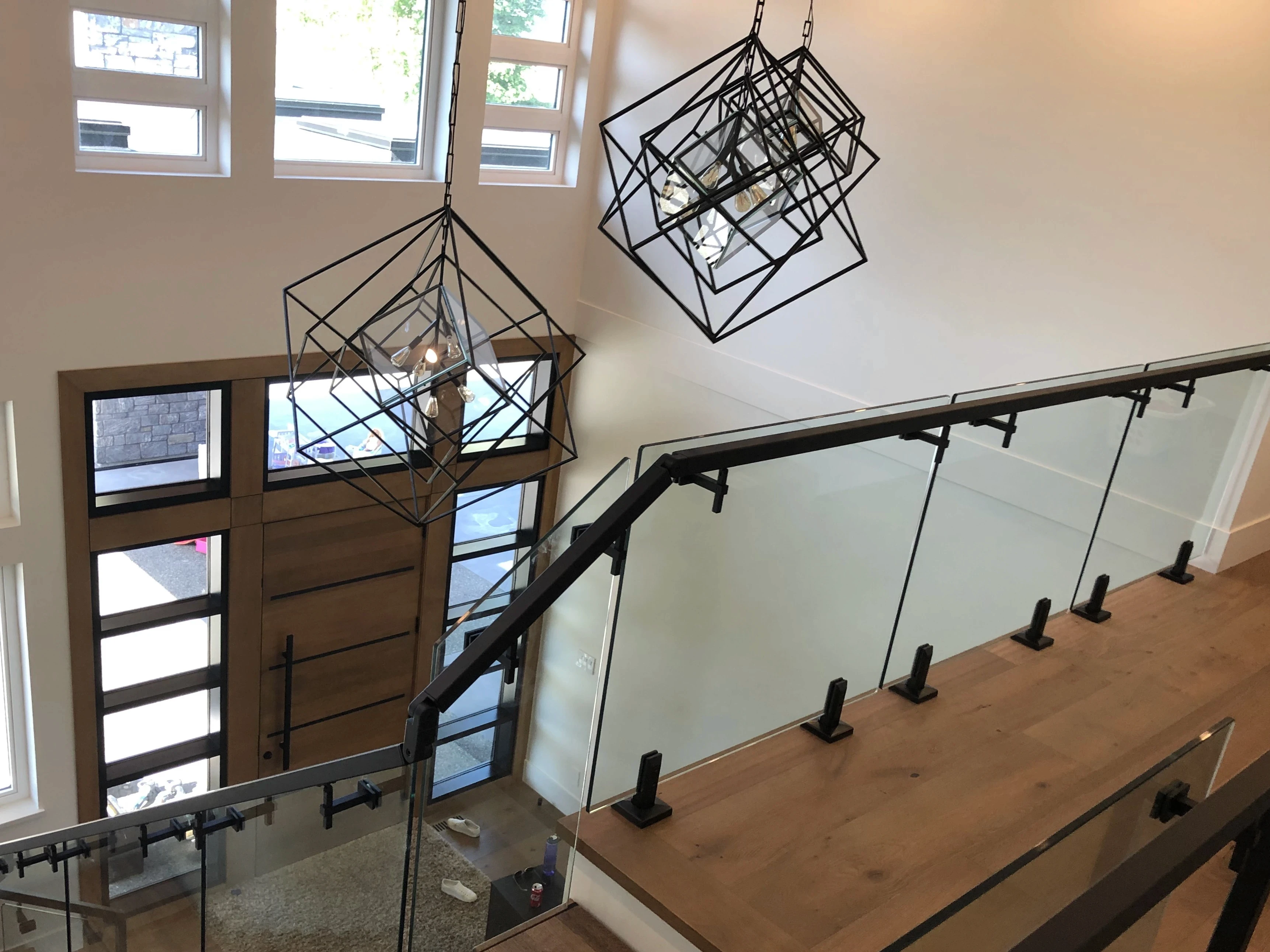 Interior spigot glass railing on an upper landing with black base mounted spigots and a black handrail across the top.