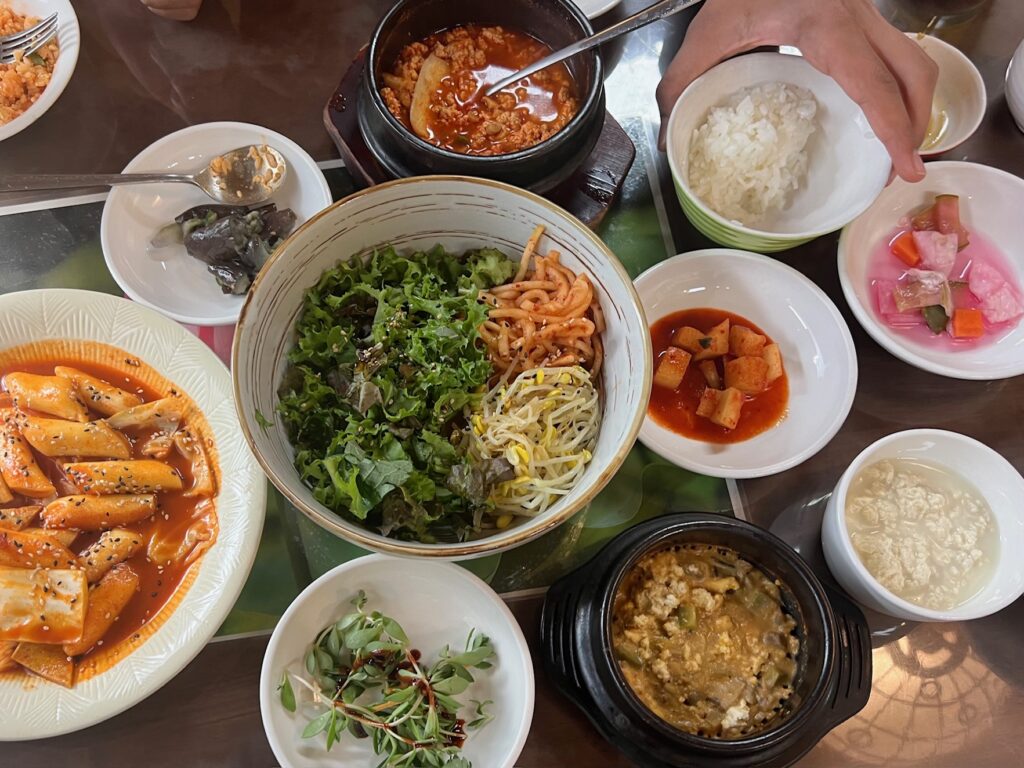 Bibimbap and kimchis are served on a table.