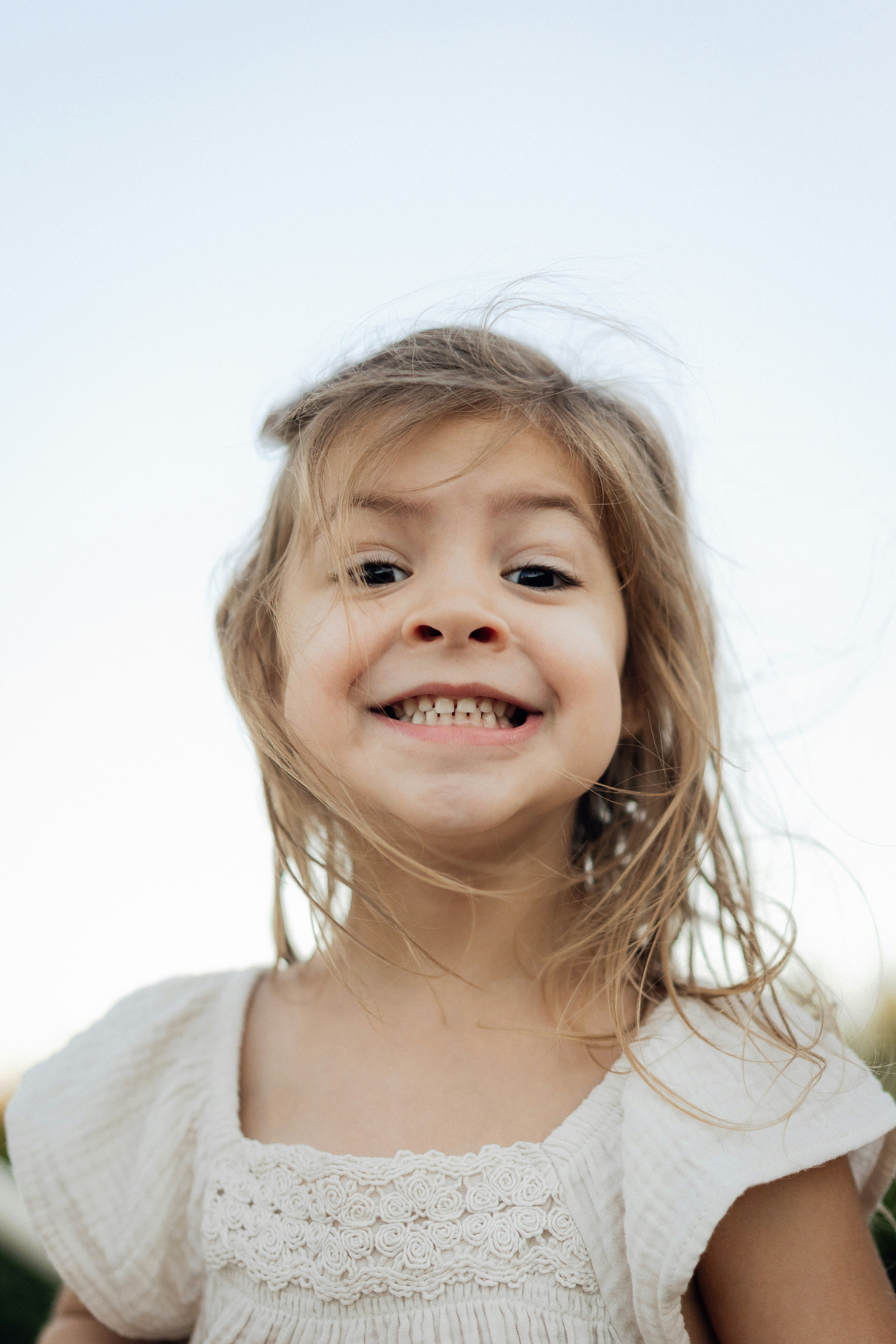 A young girl smiles widely with windblown hair.