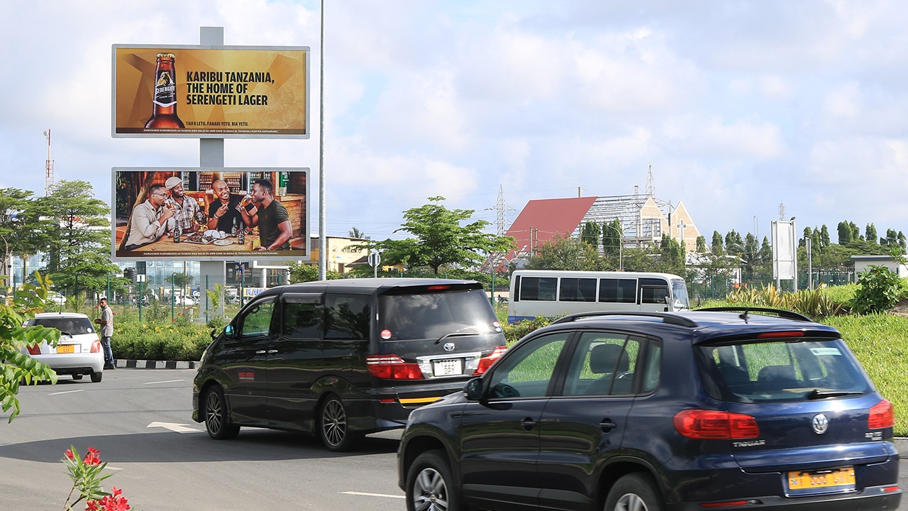 Brick waterfront building with large glass windows, reflecting the warm glow of a sunset over the river.