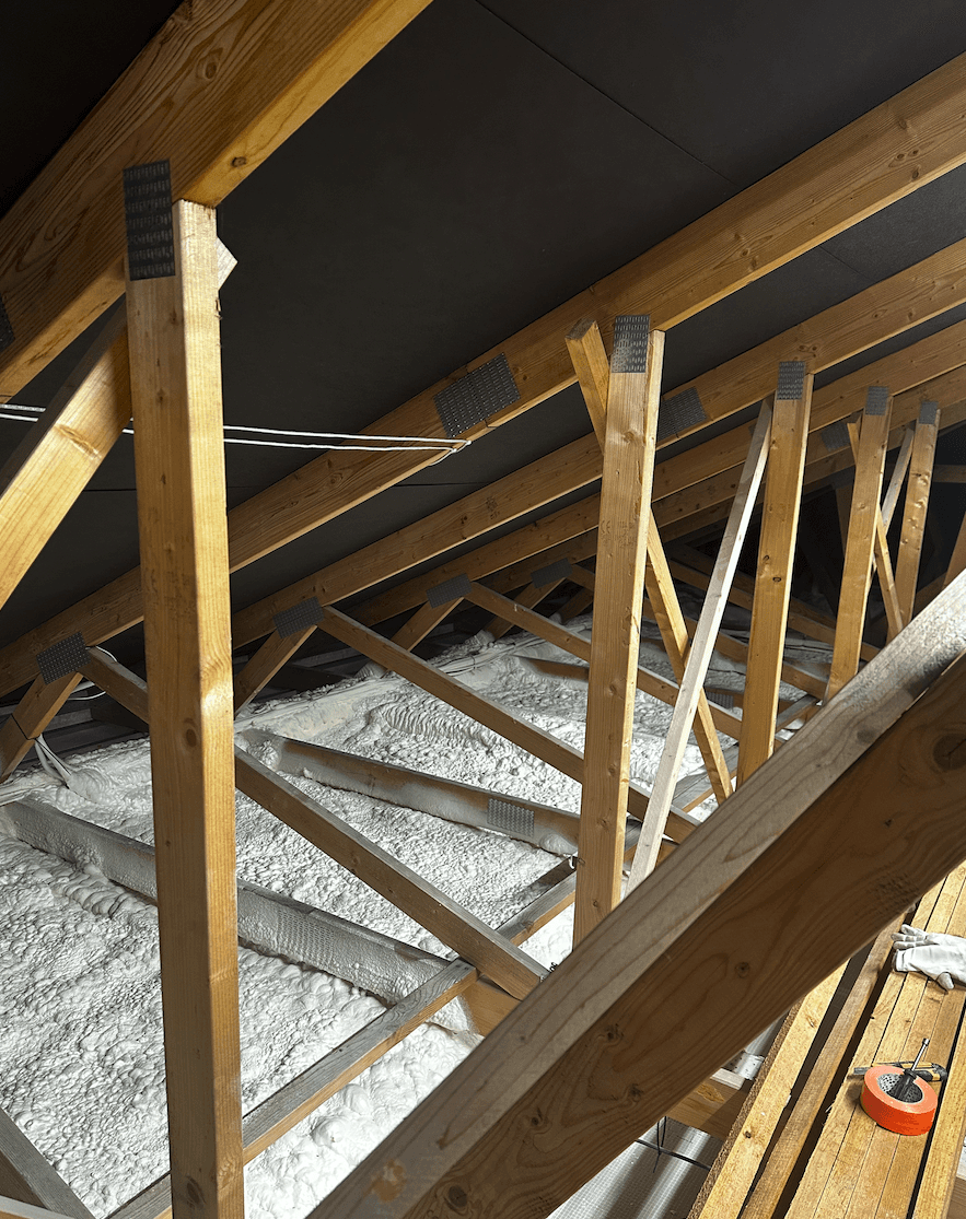 A smiling woman with her arms crossed, standing against a dark green background. She has long, dark hair.