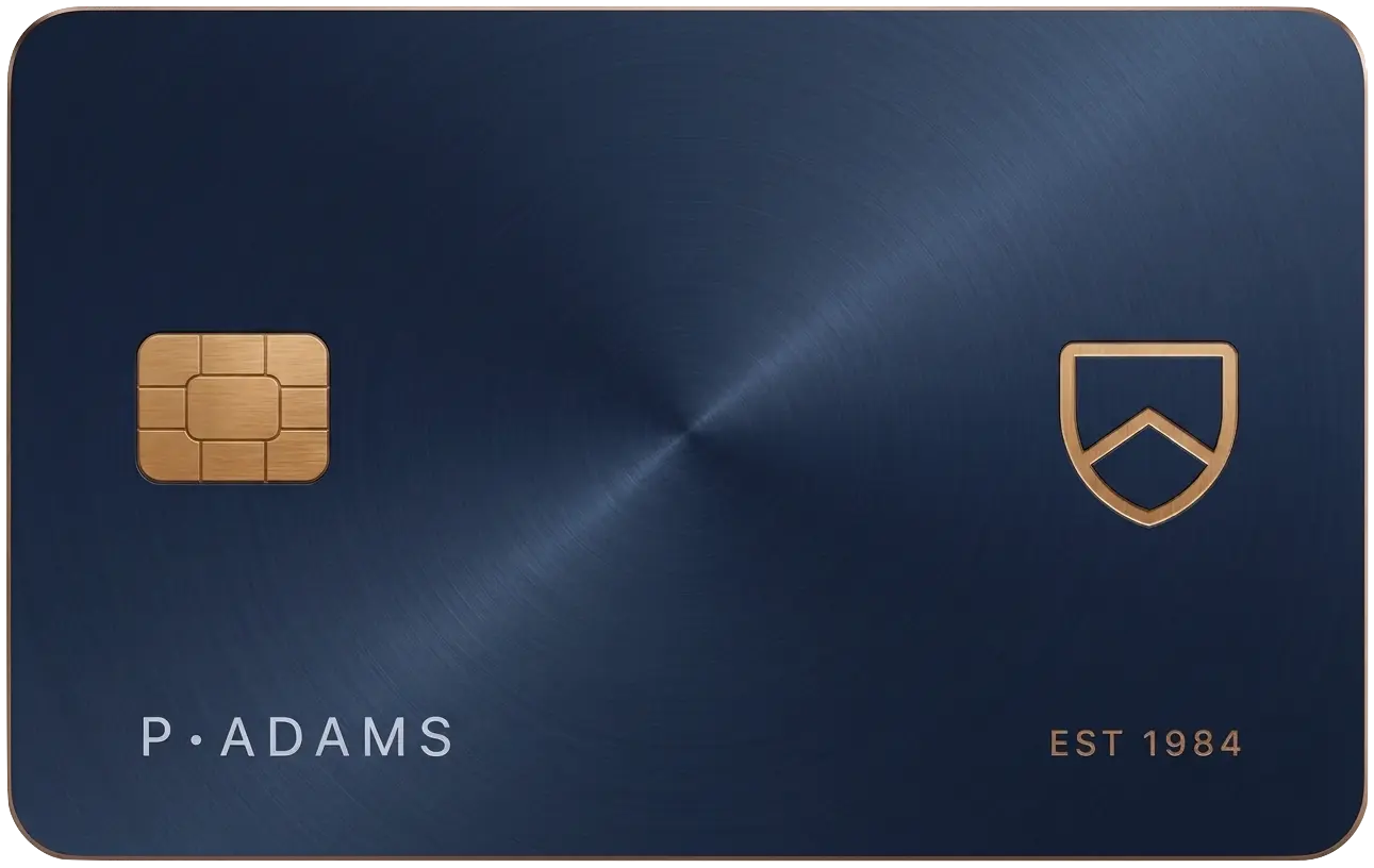 Custom navy metal card with gold chip, shield-and-chevron monogram, and engraved lettering: P. Adams, est. 1984.