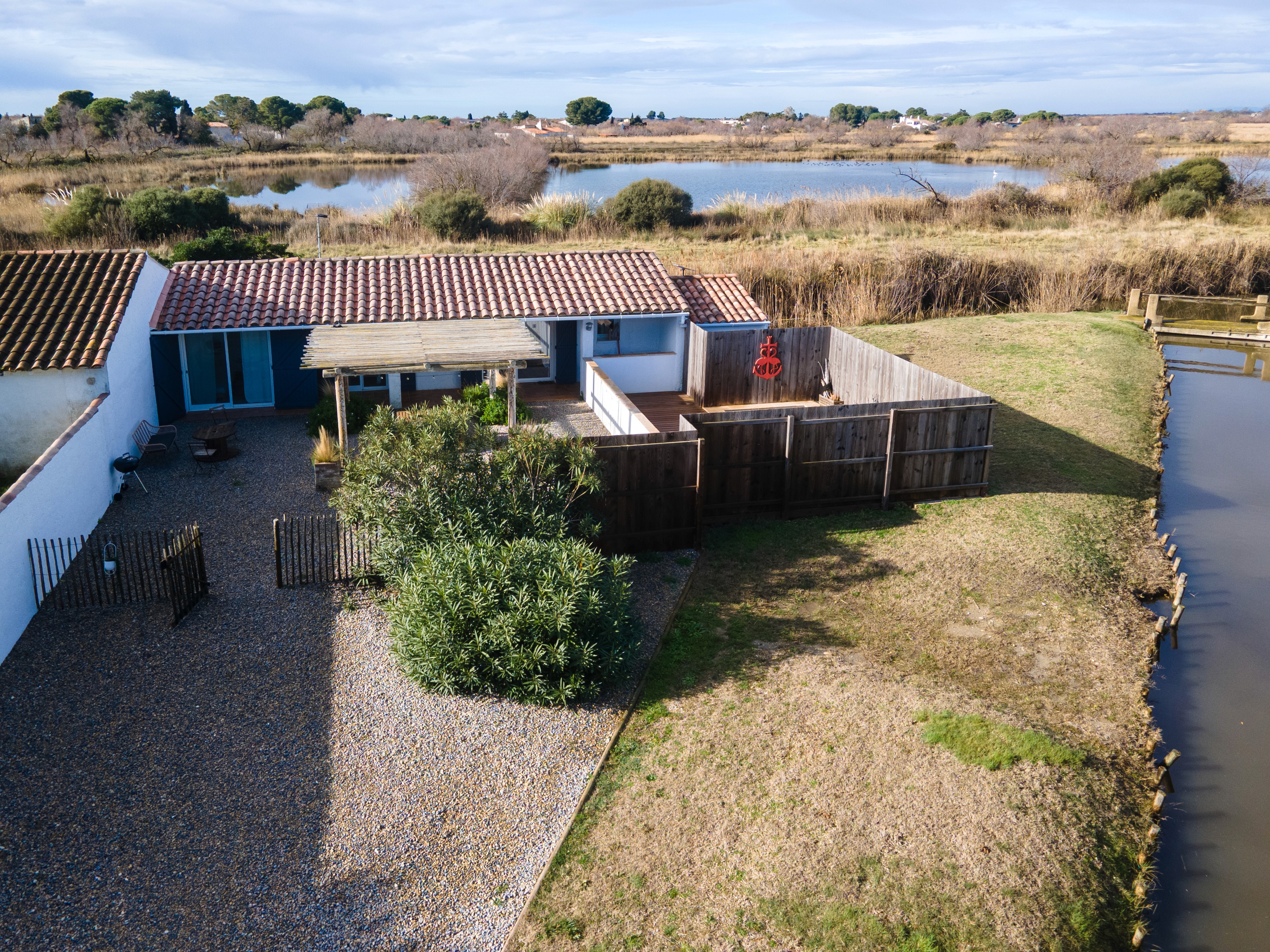 Vue aérienne d'une maison de vacances avec terrasse privée en bois, jardin clos et vue imprenable sur les étangs et la nature sauvage.