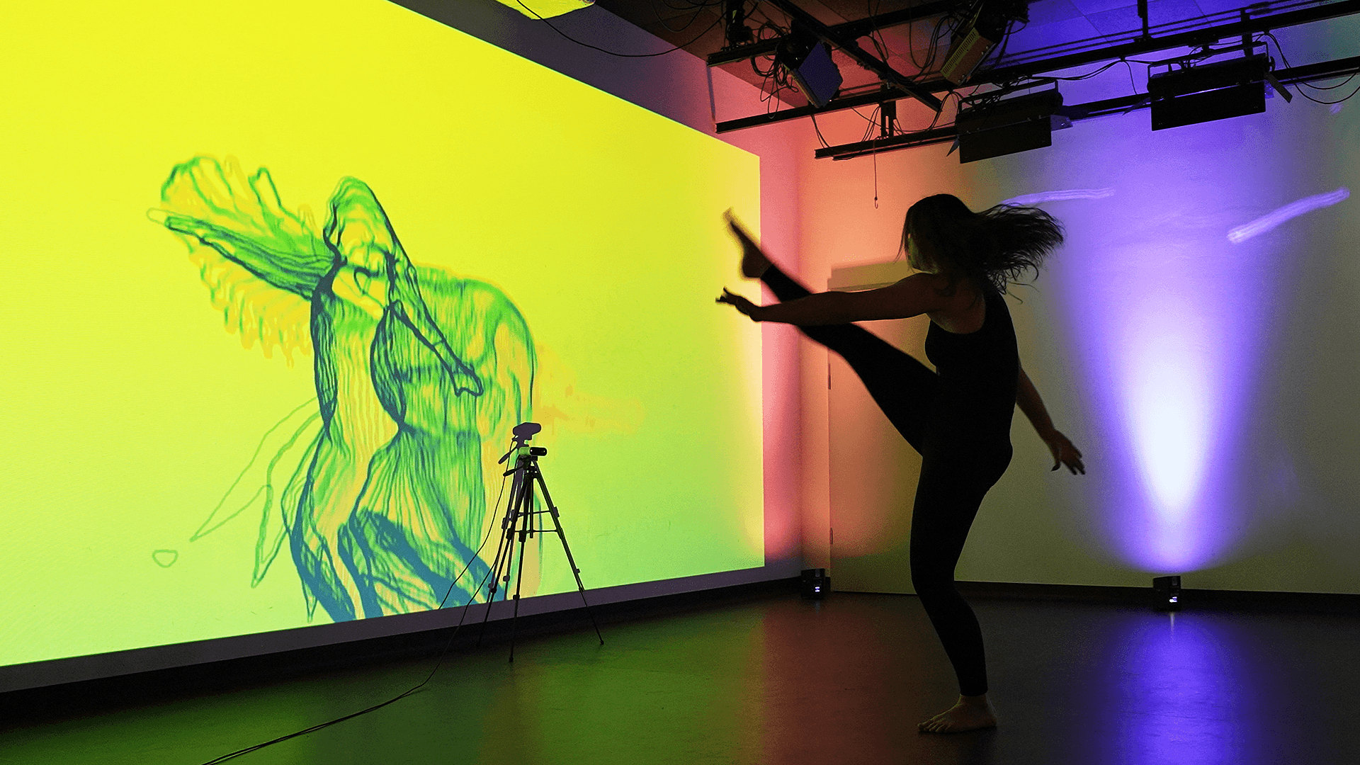 Dancer silhouette in front of a wall projection with generative particle visuals