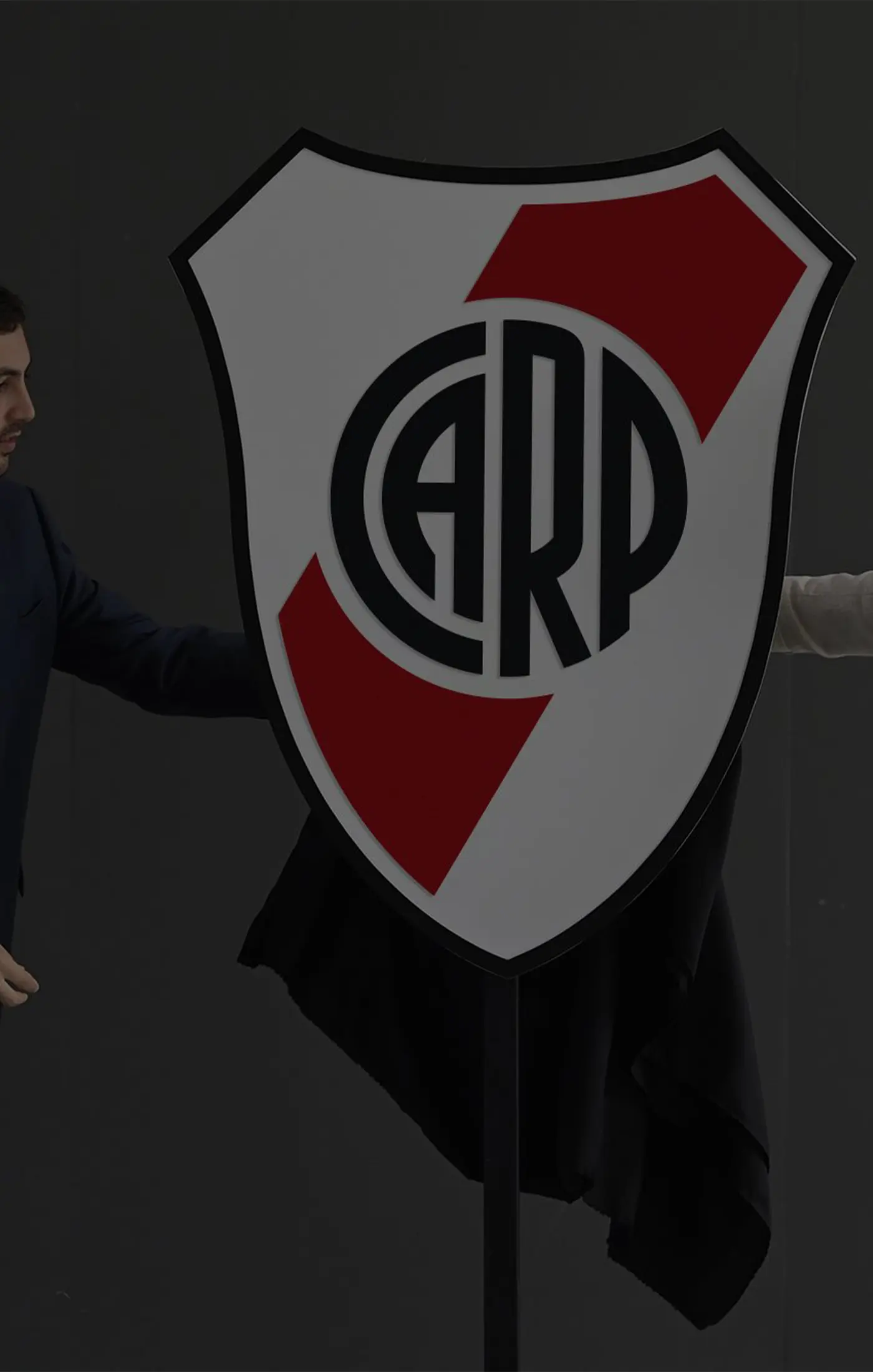 Three men in business attire reveal a large shield-shaped logo.