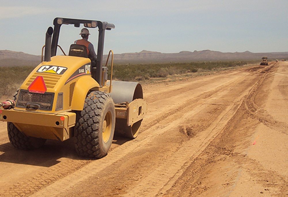 Roller compacting roadway subgrade to meet compaction requirements before paving.