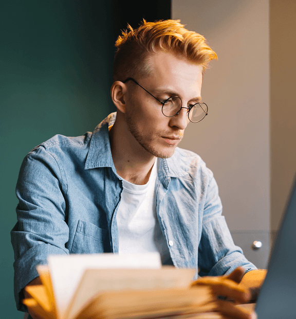 A college student in glasses studying at a desk