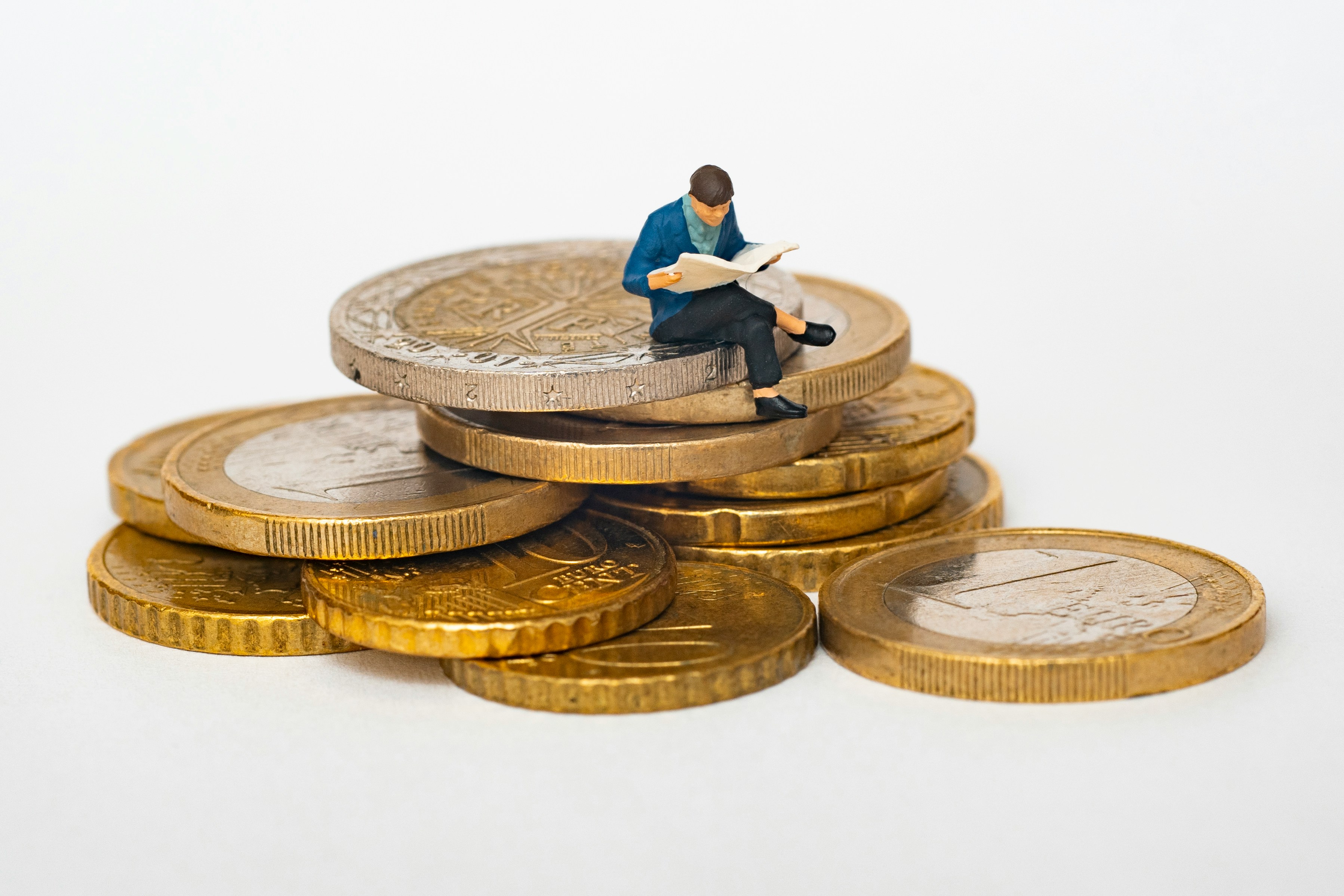 A toy man sitting on a stack of euro coins