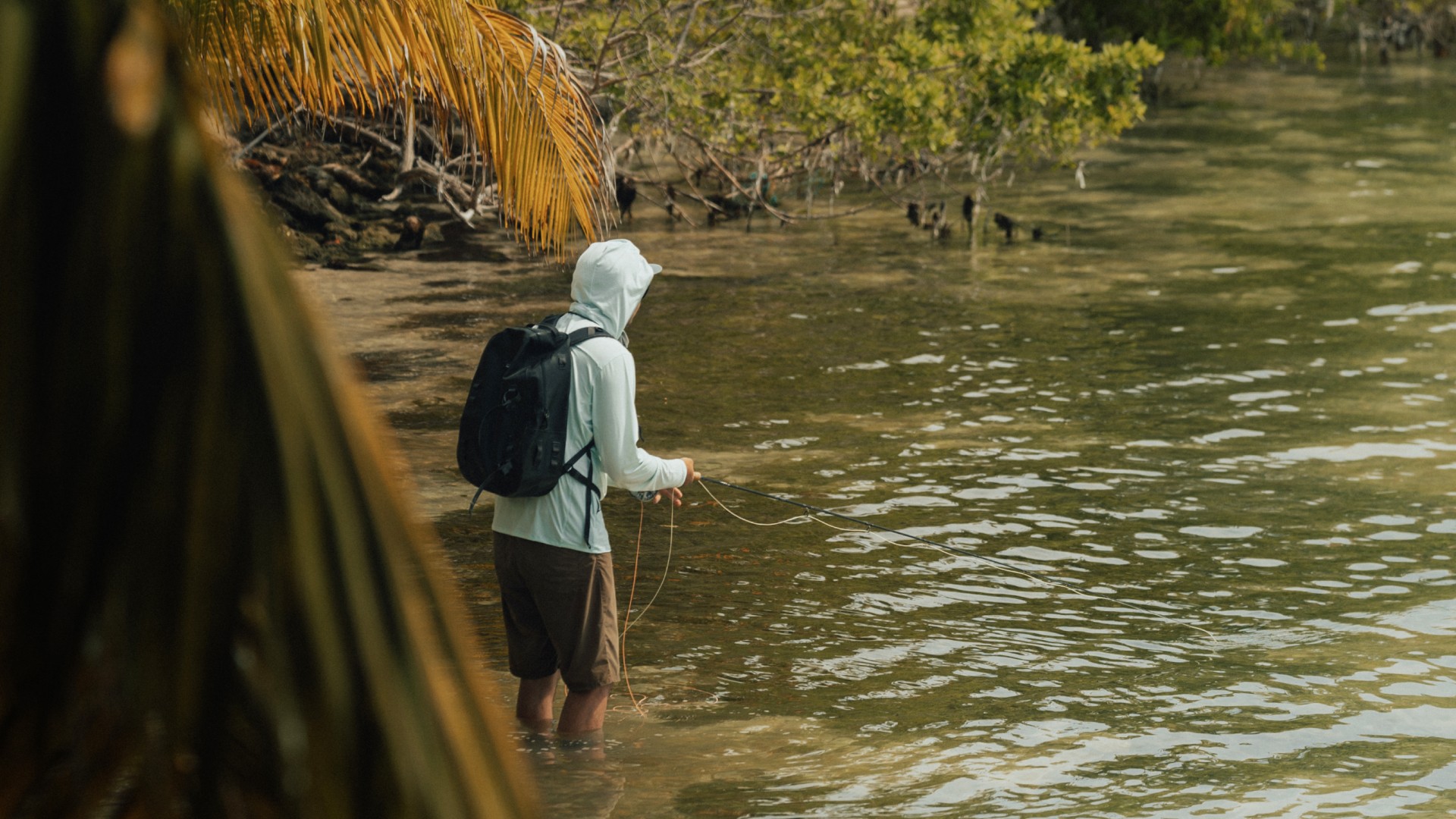 Angler fishing for bonefish in shallow water on South Water Caye, Belize