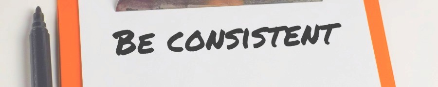 handwriten "be consistent" on a sheet of papper with a black marker next to it