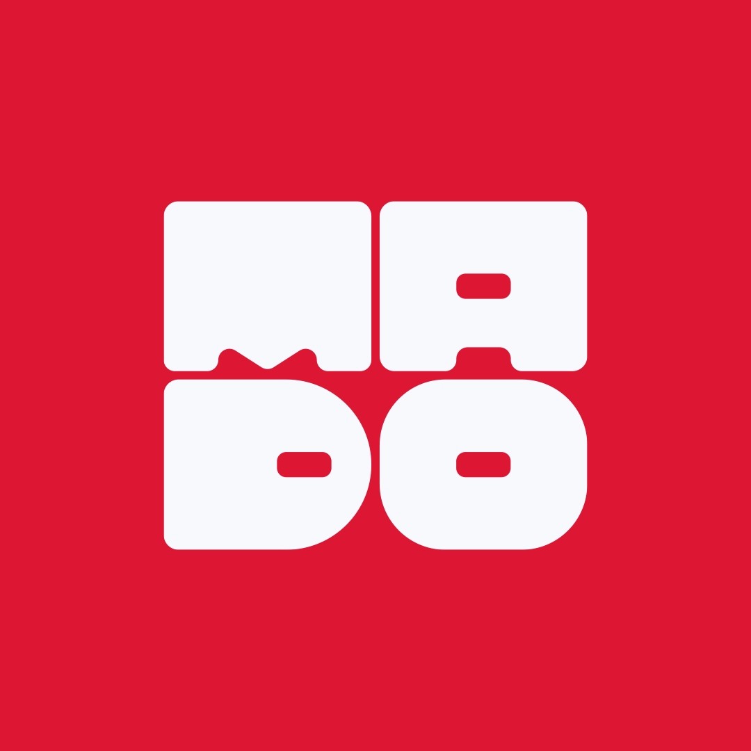 Man with brown hair wearing a black turtleneck and blazer, smiling slightly. The background is softly blurred, suggesting an outdoor, sunny setting.