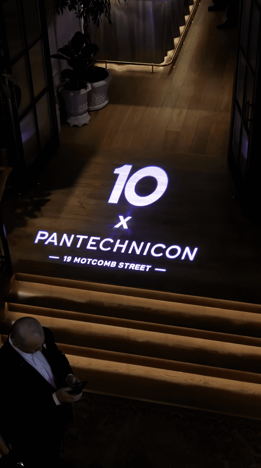 Bride sitting on ground against wall, groom standing nearby