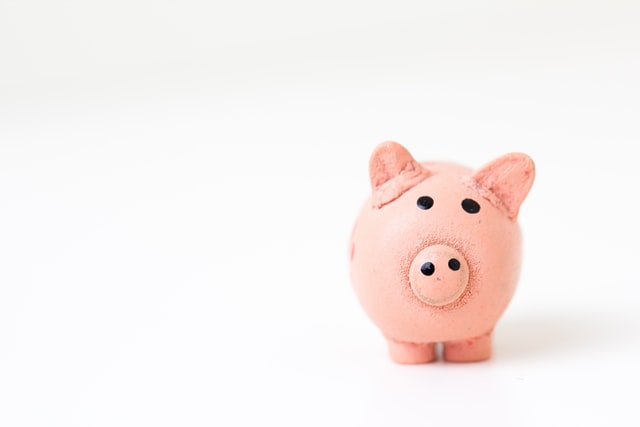 Small pink piggy bank on a plain background.