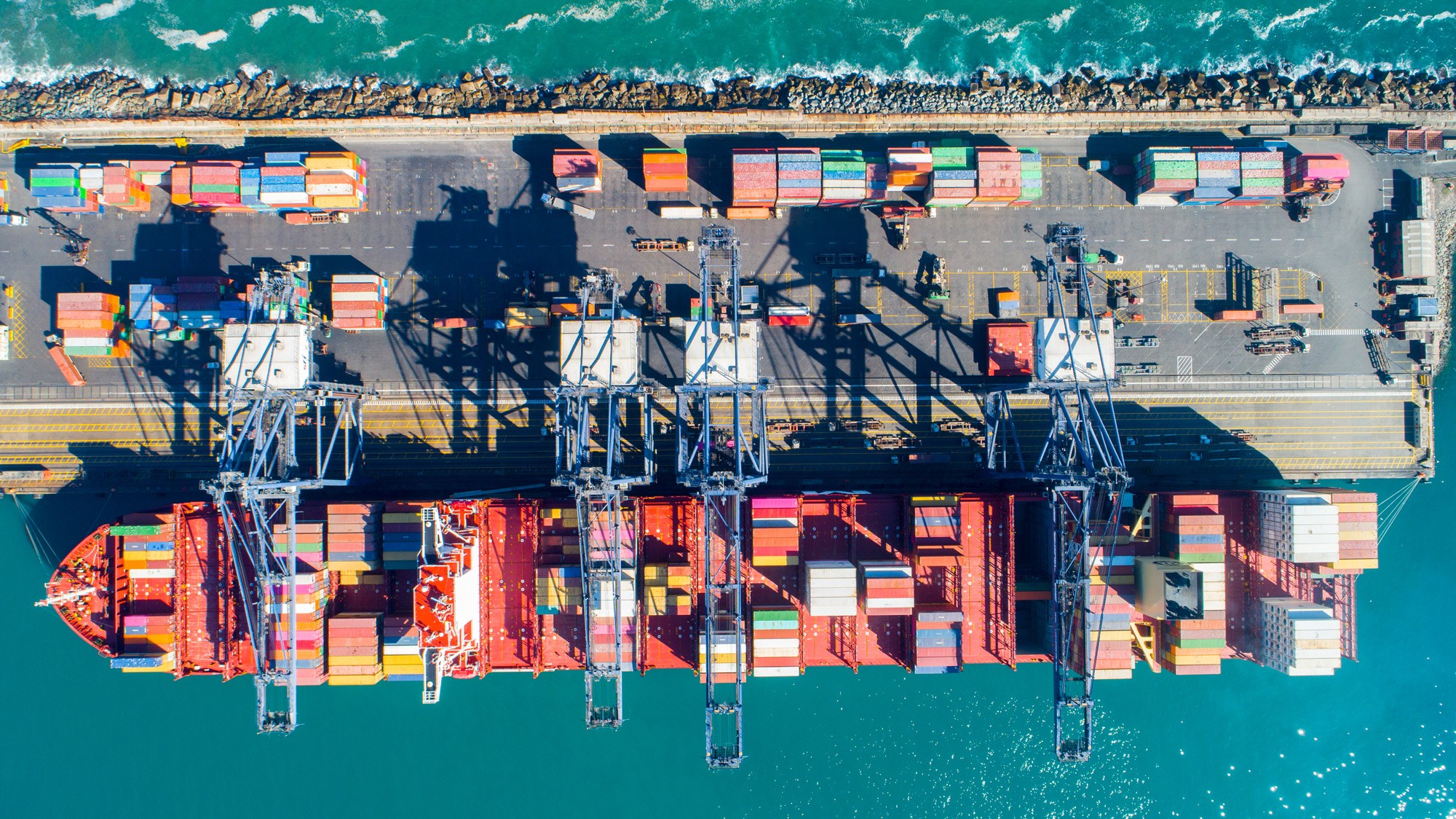 Container terminal with cranes and cargo ship (aerial view)