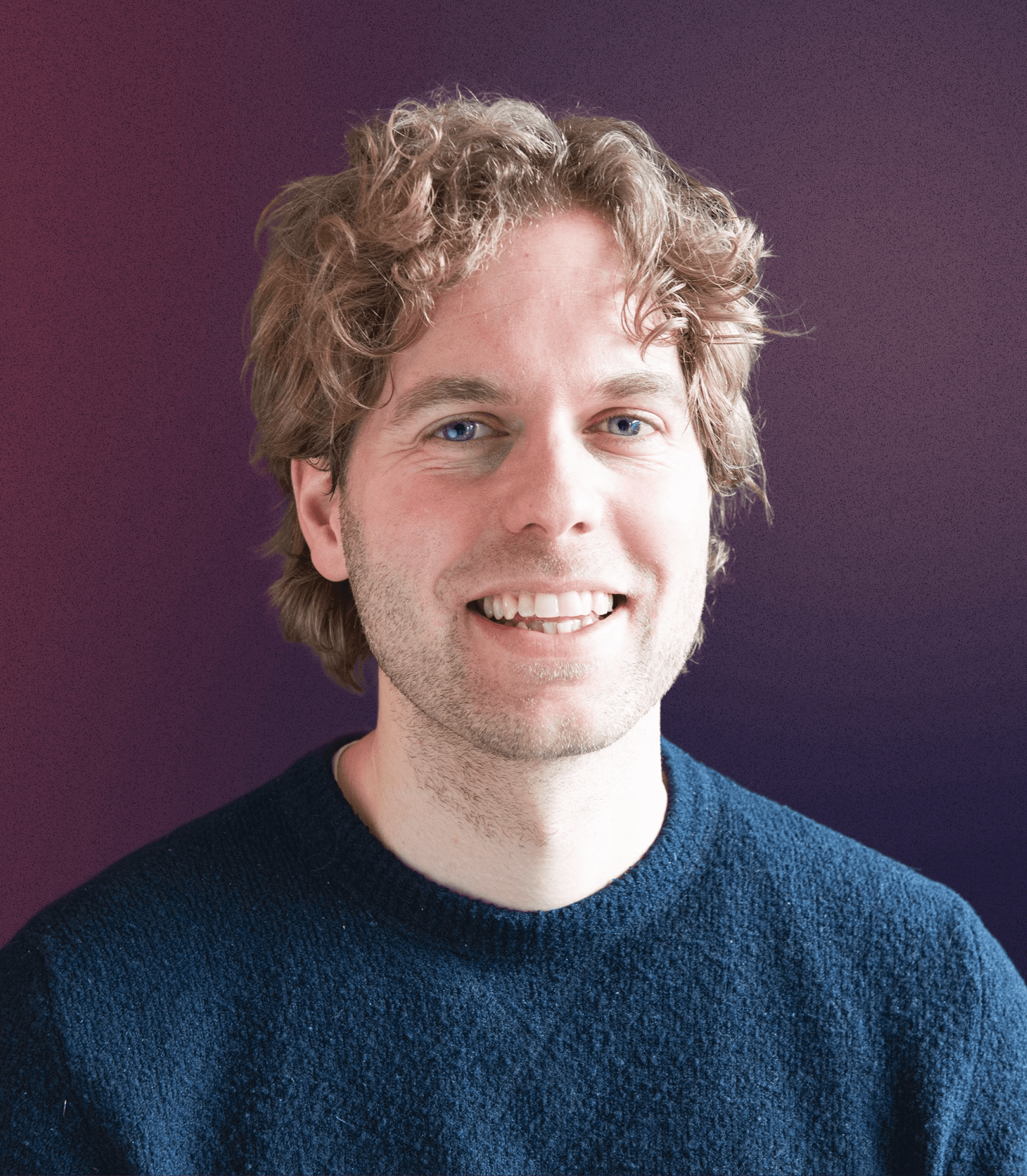 Portrait of a young man in a brown coat and beige turtleneck, with light brown hair and a calm expression against a gray background.