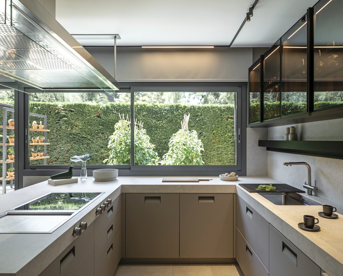 Cocina Arclinea con muebles y encimera en tonos grises y ventana grande al jardín