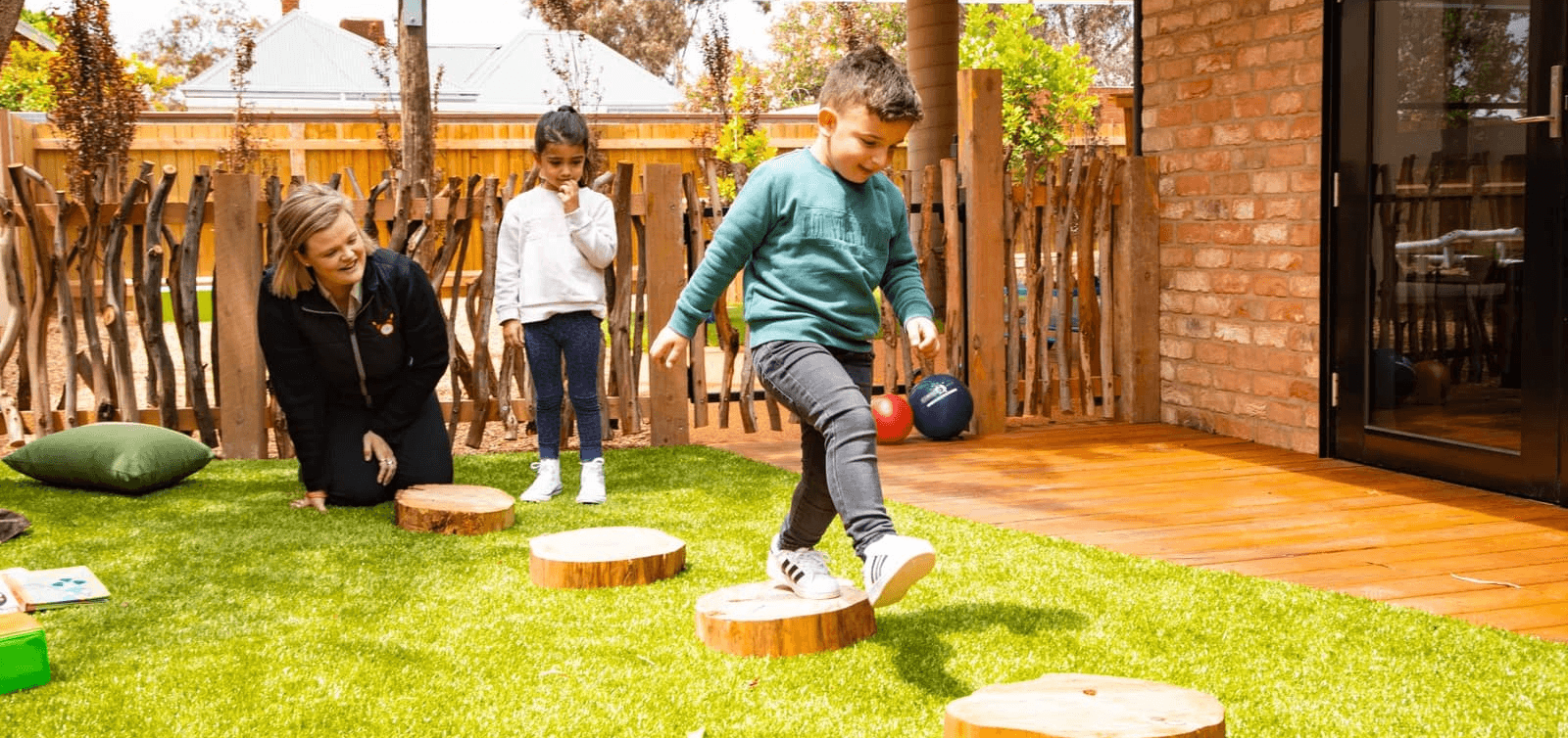 Children walking on wooden stepping stones with educator