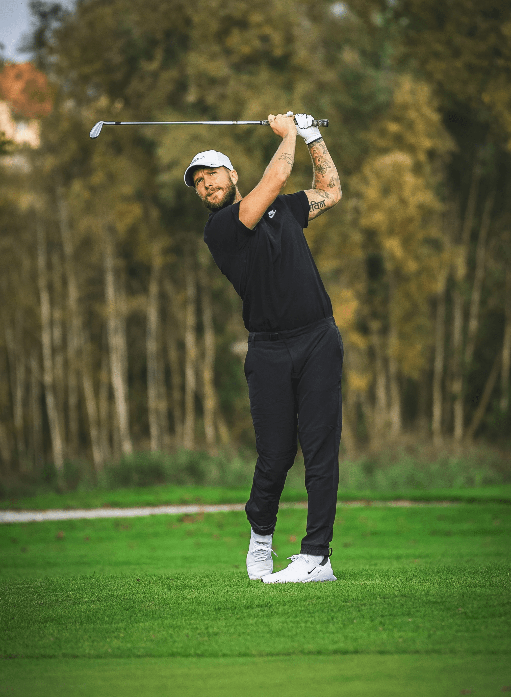 a man swinging a golf club on top of a green field