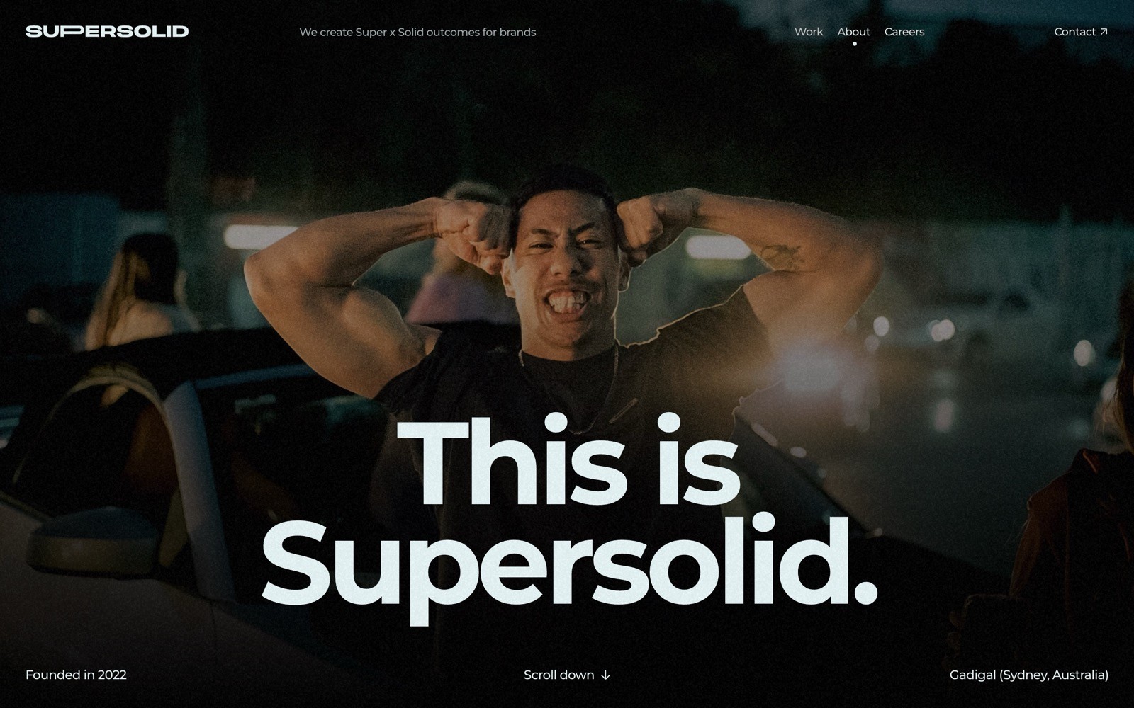 A person flexes their arms at night with lights in the background. Bold text reads, "This is Supersolid." Menu options in the top right.