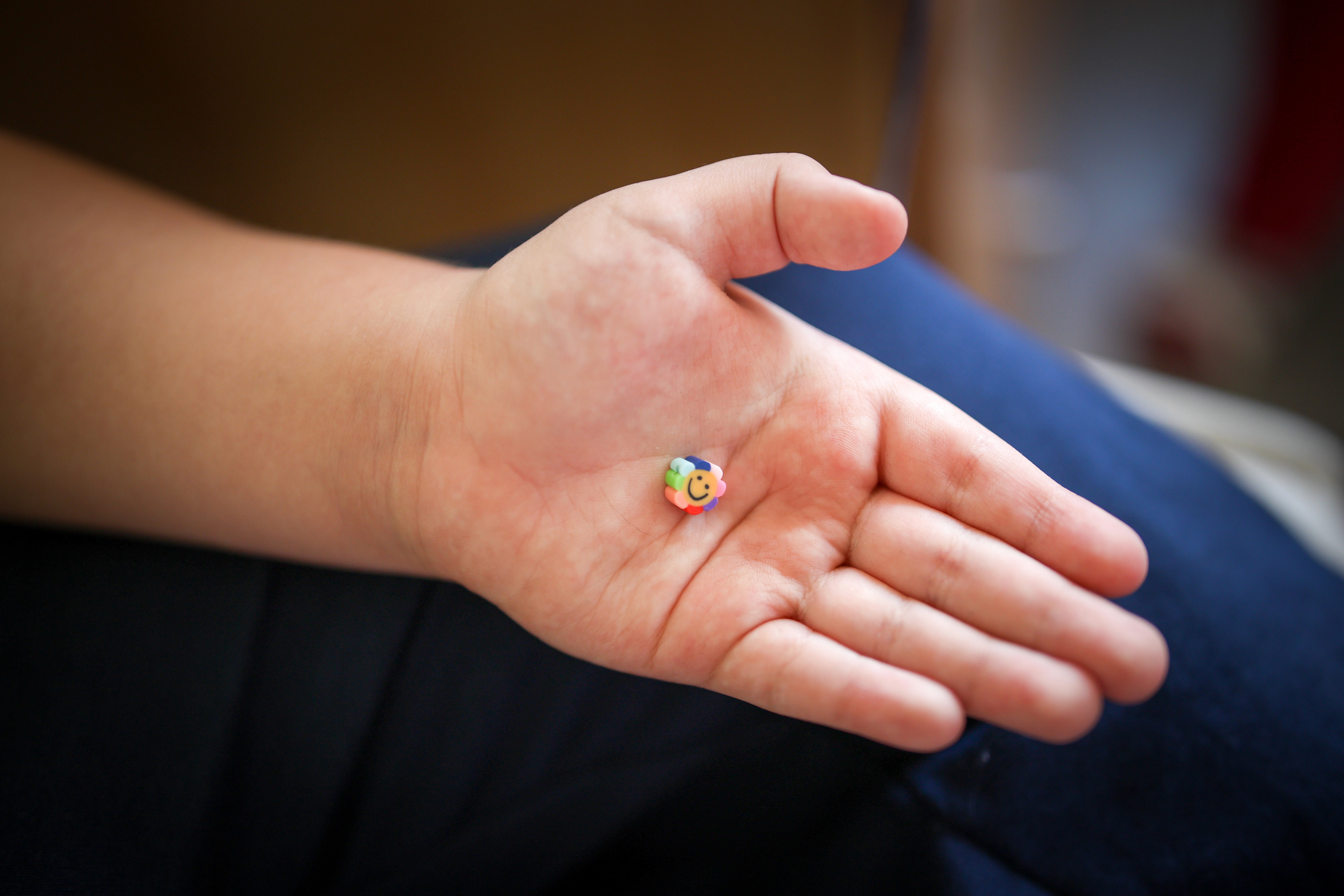 Kisgyermek kinyújtött kezében, egy mosolygós színes virágalakú radír. 