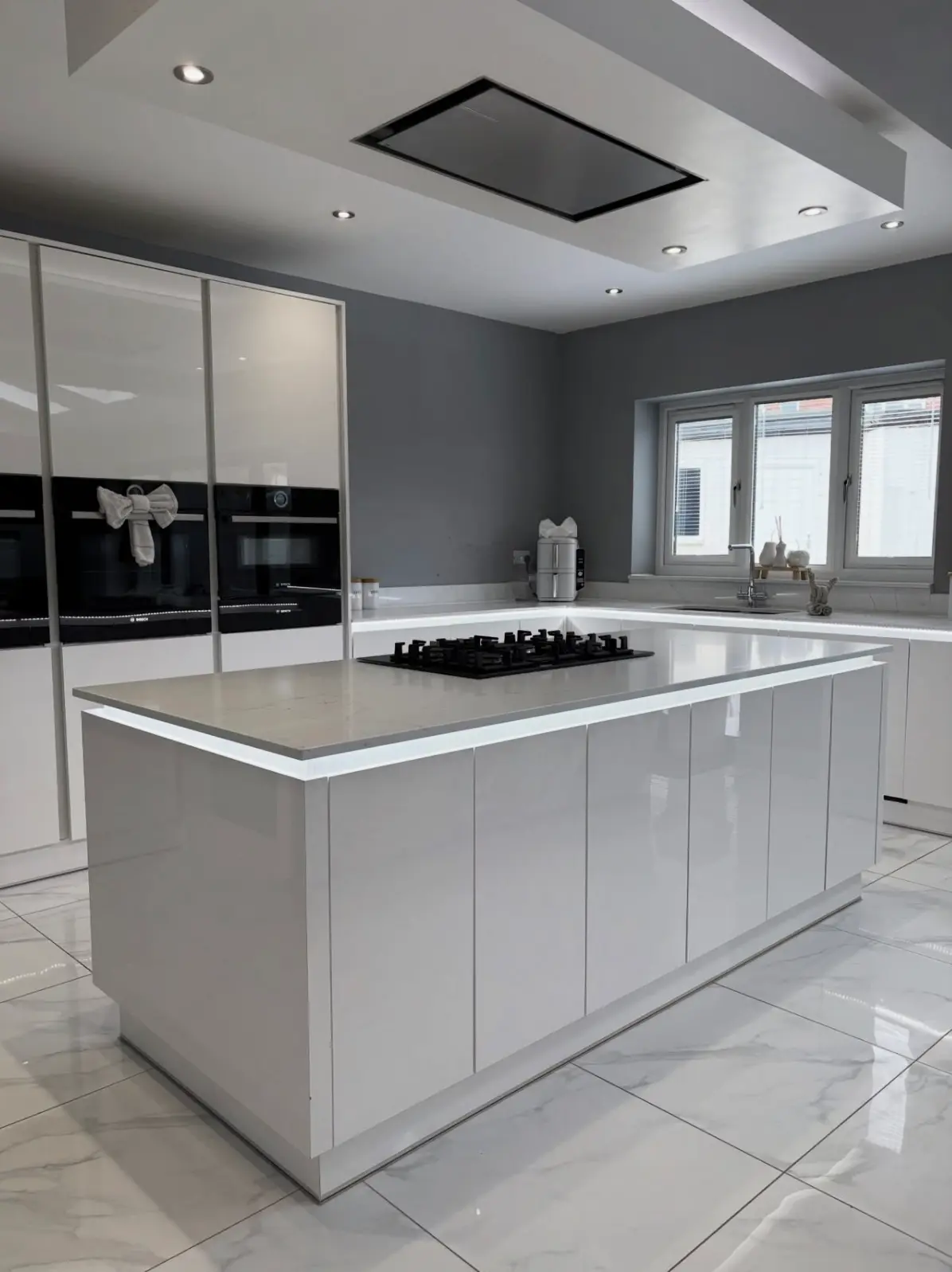 A modern high-gloss kitchen following a post-construction clean, featuring polished marble floor tiles, streak-free cabinetry, and a sanitized island with integrated lighting.