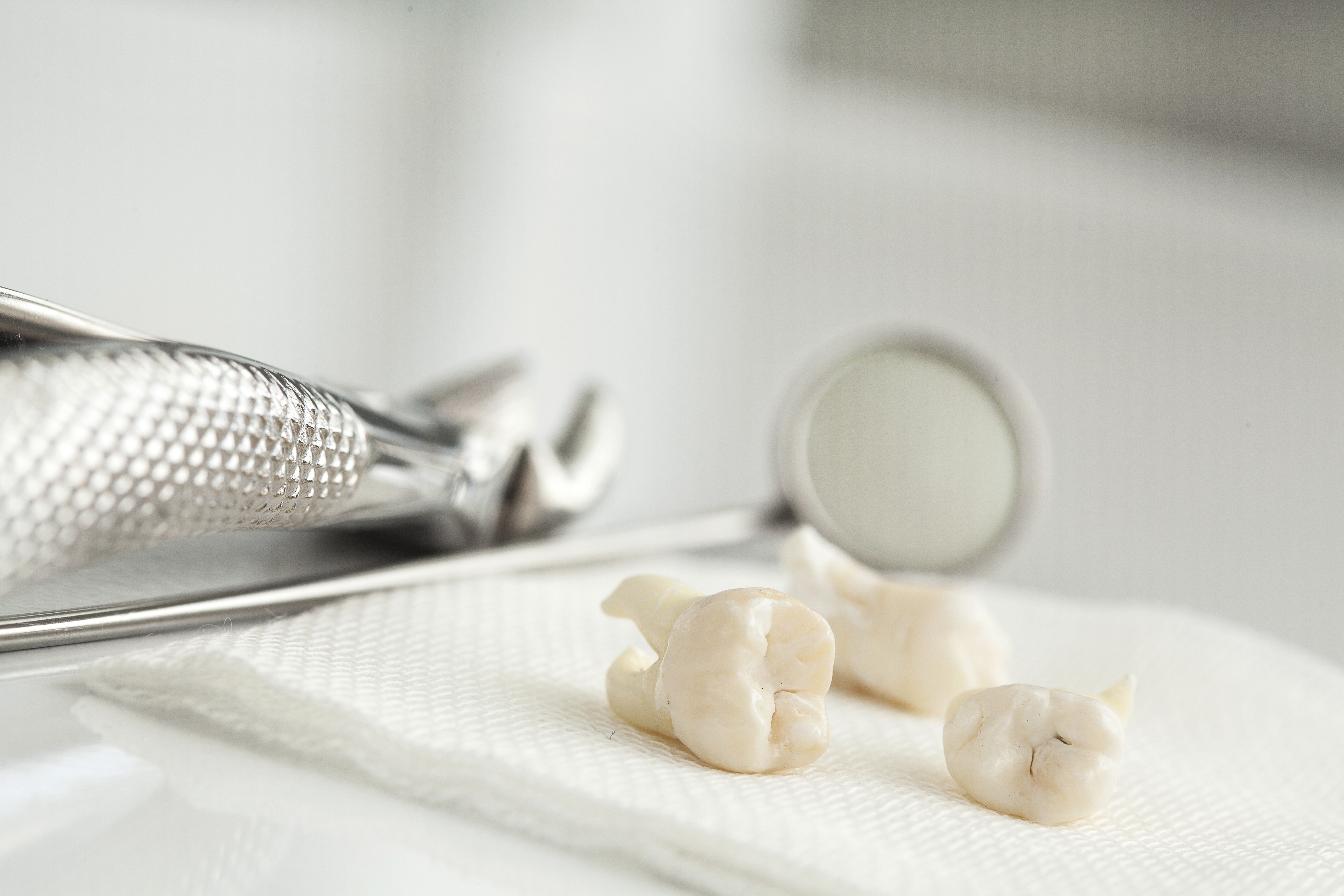 A dental mirror and tools rest on a white surface, ready for use in a clinical setting.