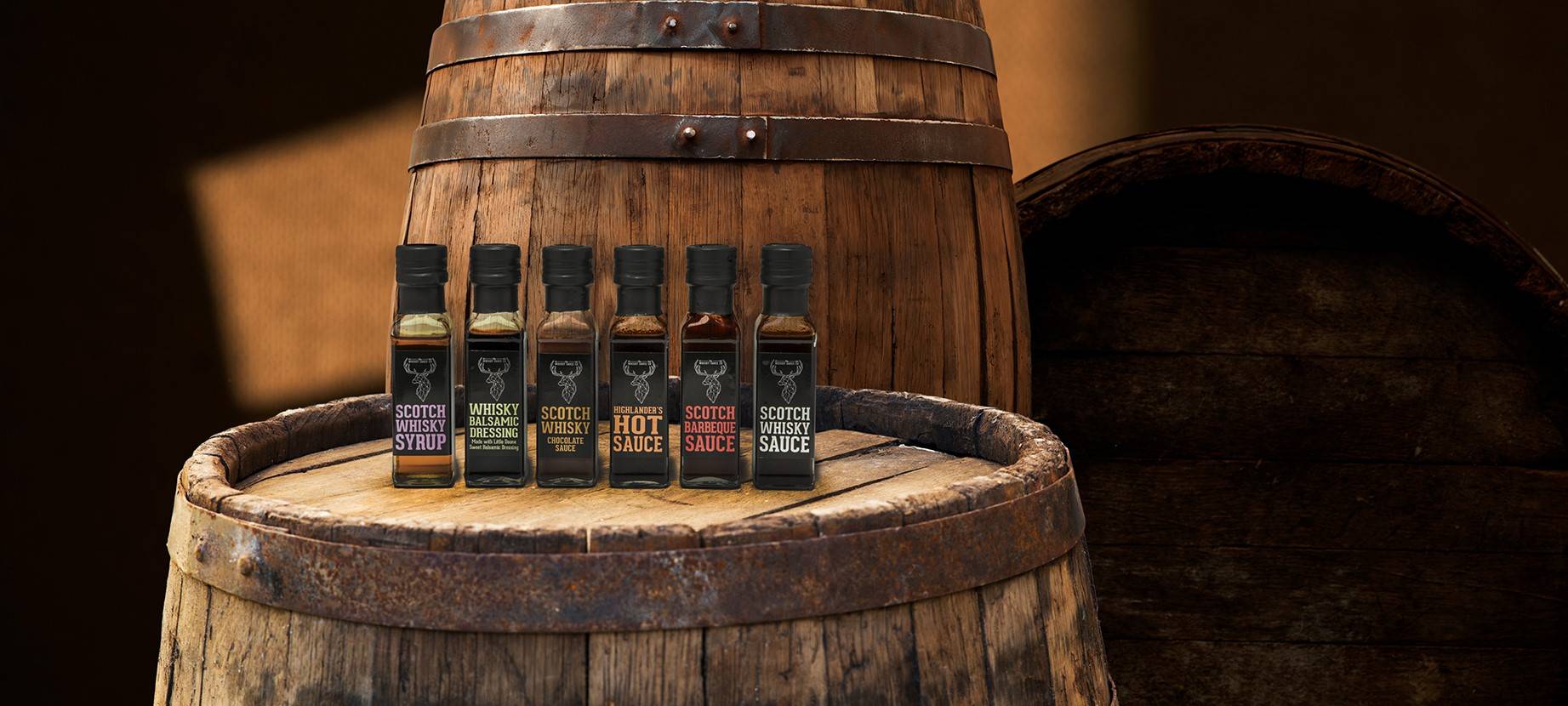 All whisky sauce products sat on a whisky barrel with a dark background 