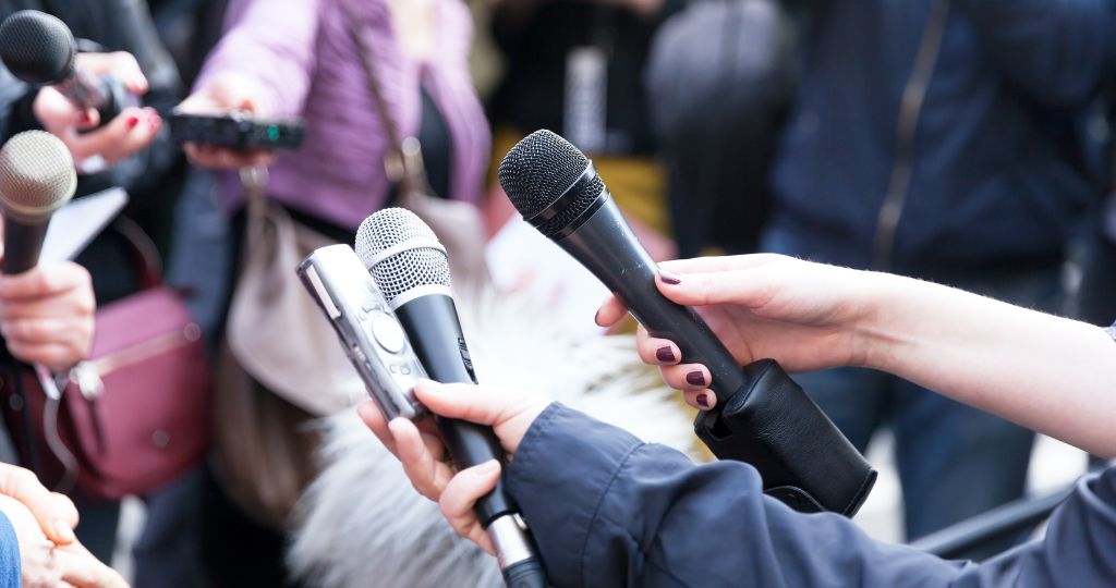 Journalists holding microphones during a press event