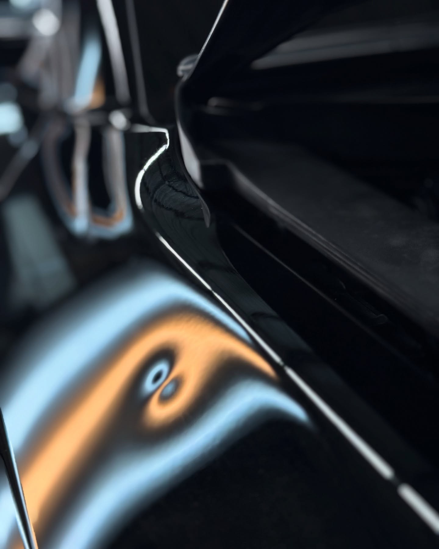 Professional paintless dent removal repairing a small dent on a black vehicle without paint or body filler