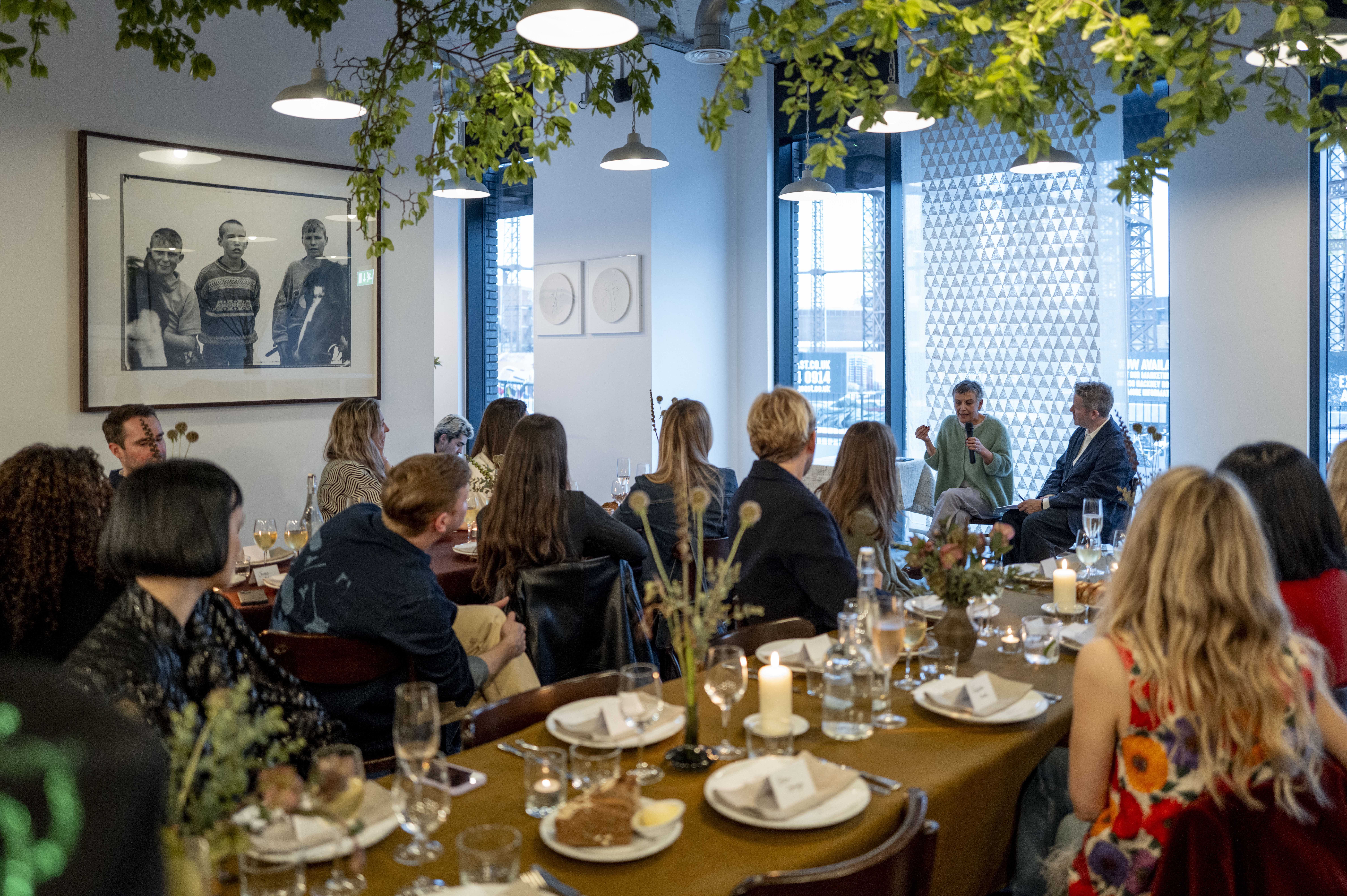 Bride sitting on ground against wall, groom standing nearby