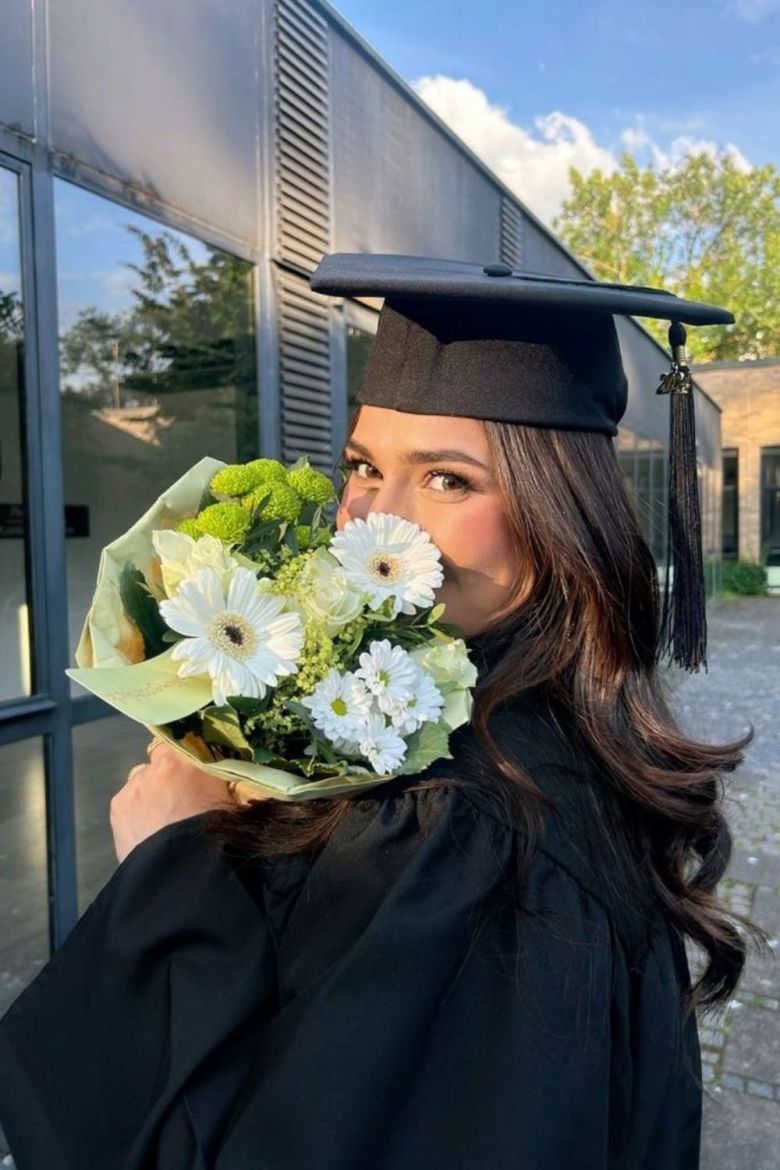 A sunlit portrait of a woman in elegant summer attire, wearing a striped headscarf and gold hoop earrings