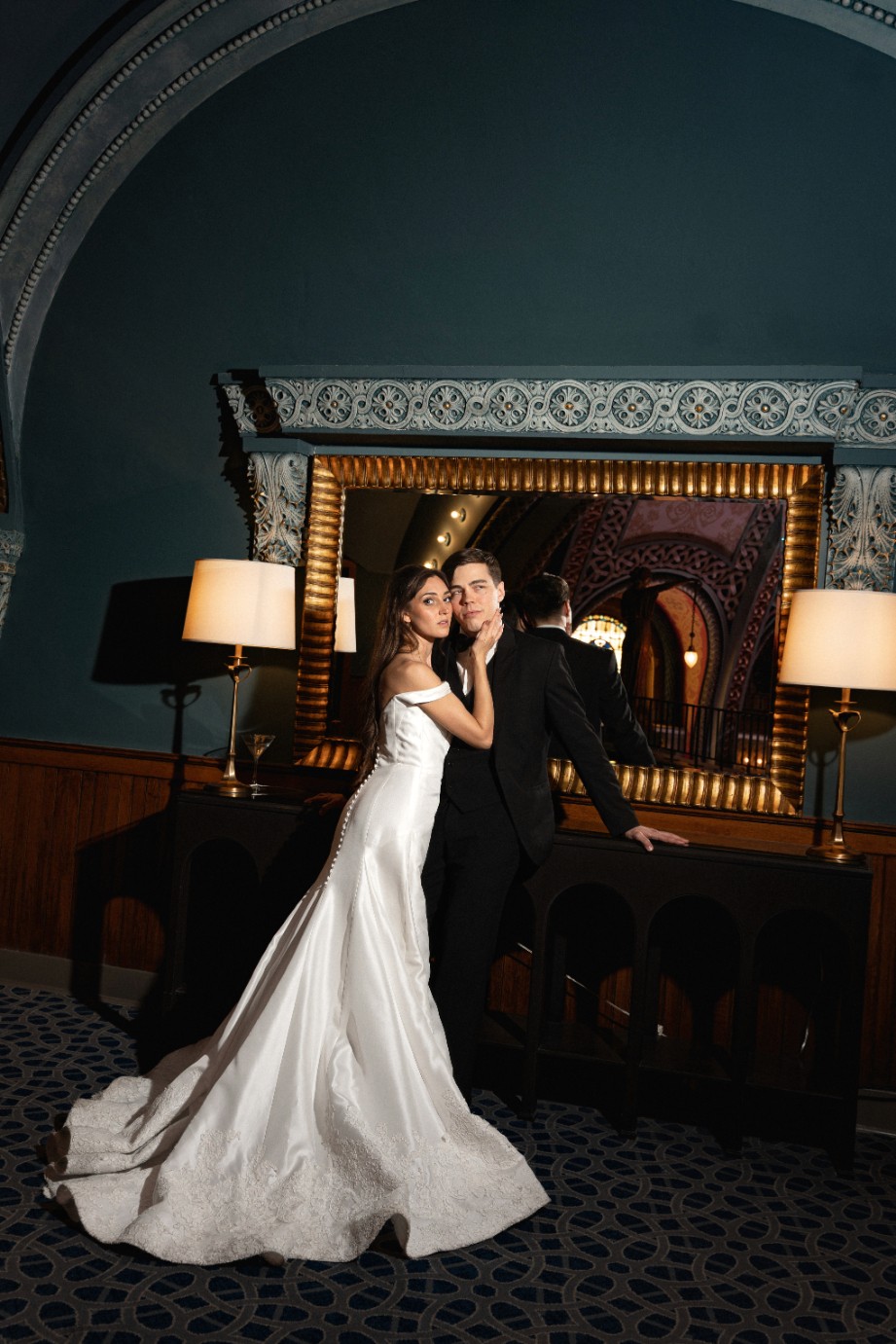 A joyful couple stands back-to-back outdoors.