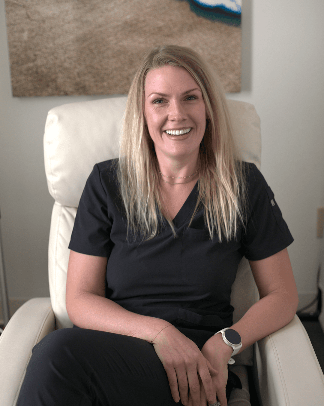 Woman with shoulder-length dark hair wearing a brown sweater, smiling at the camera.