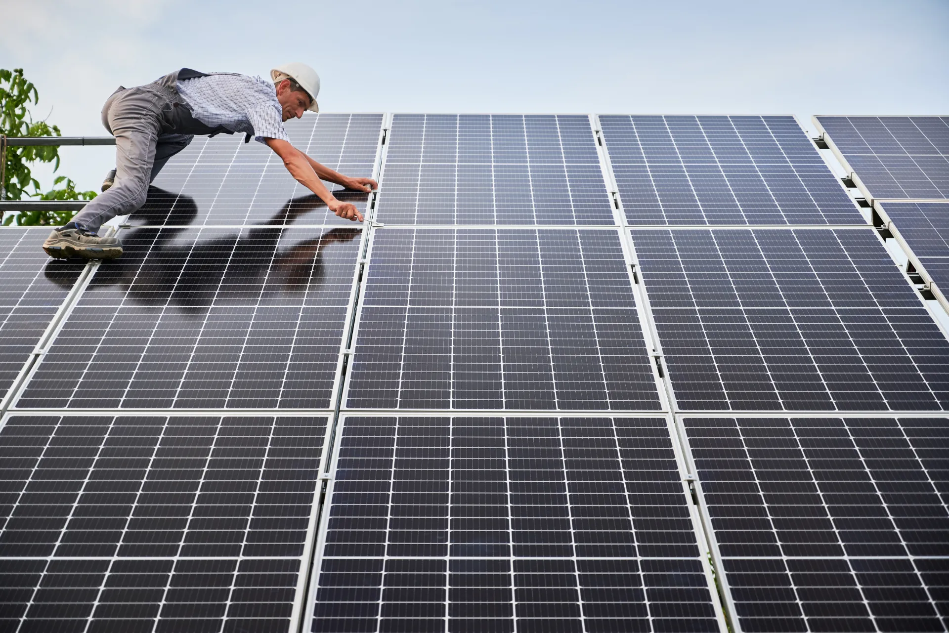 Photovoltaikanlage auf einem Dach, welche gerade von einem Menschen montiert wird.