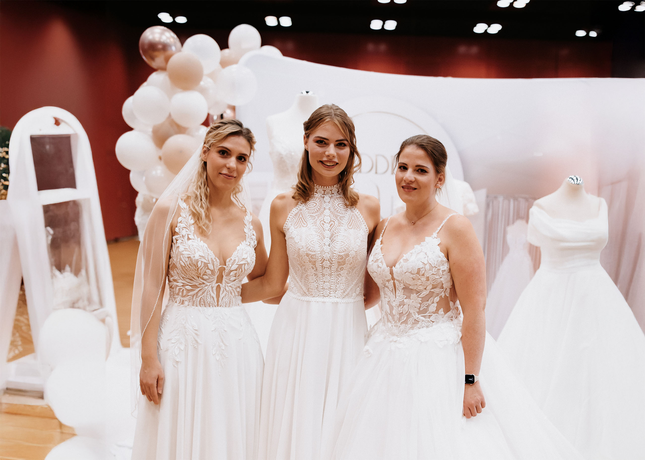 Eine Braut in einem verspielten Hochzeitskleid mit Tüllrock und Spitzenoberteil, berät sich mit einer Beraterin.