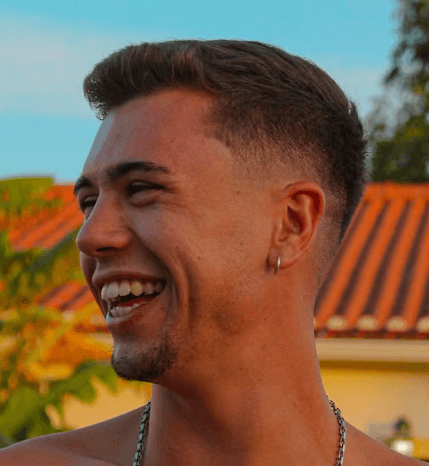 a young man wearing glasses standing in front of a mountain