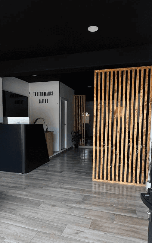 Interior de un local comercial reformado, con mostrador de recepción, separadores de madera y acabados contemporáneos en un espacio destinado a actividad profesional.