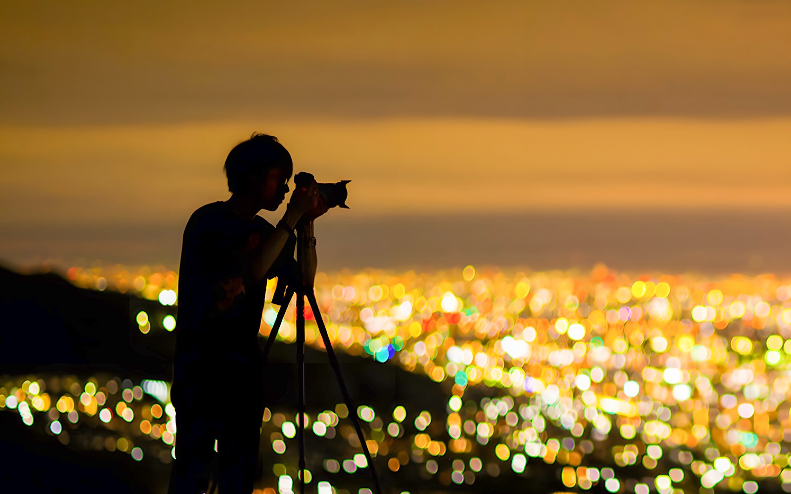 Photographer capturing Kobe city lights at night from Mt. Rokko viewpoint.