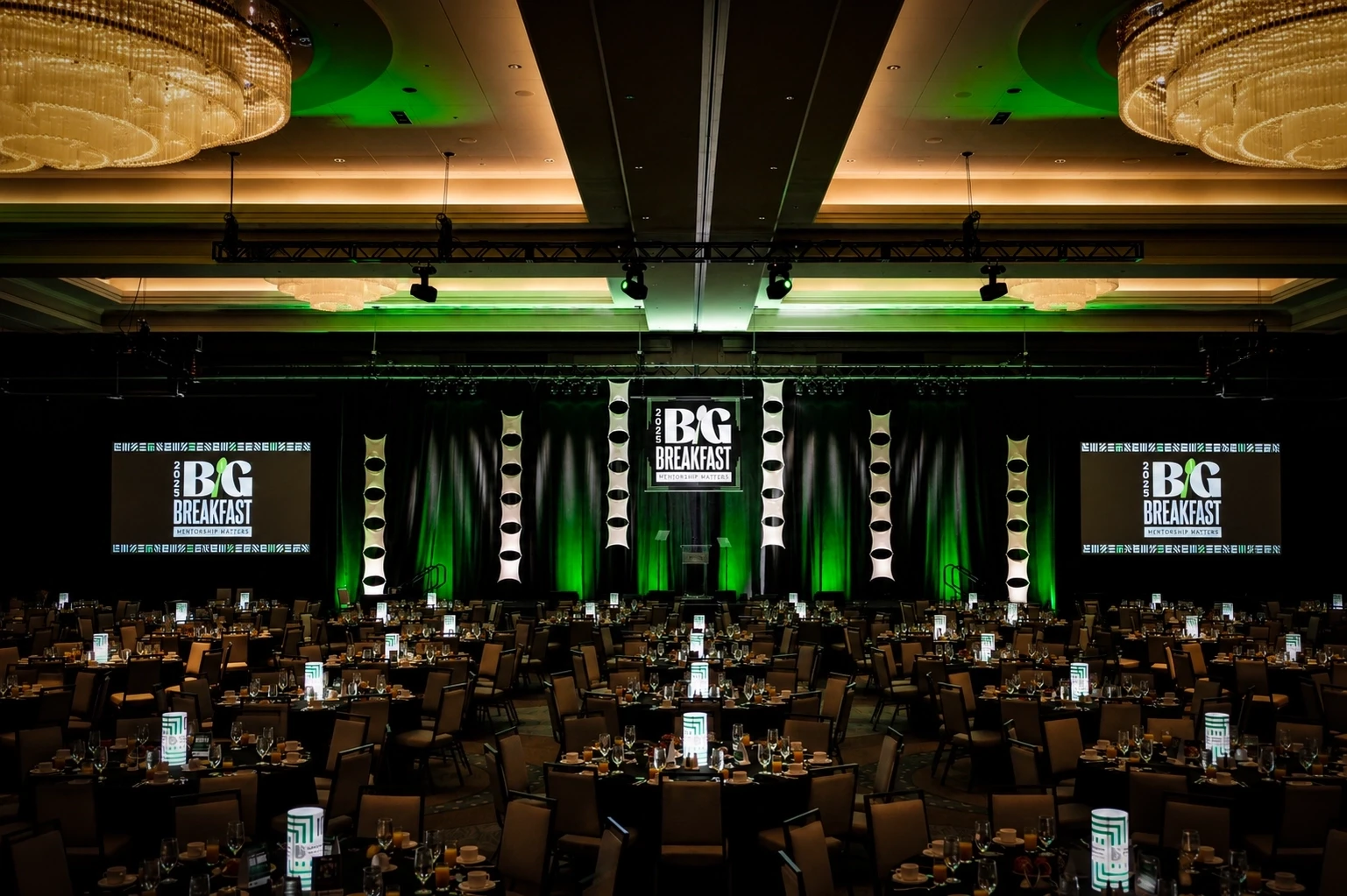 Ballroom facing the 'Big Breakfast' stage screens with green uplighting at the Big Brothers Big Sisters event, Nashville — corporate production by UpLight Technologies