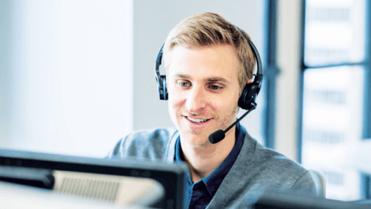 A photo of a person wearing a computer headset and looking at a computer screen