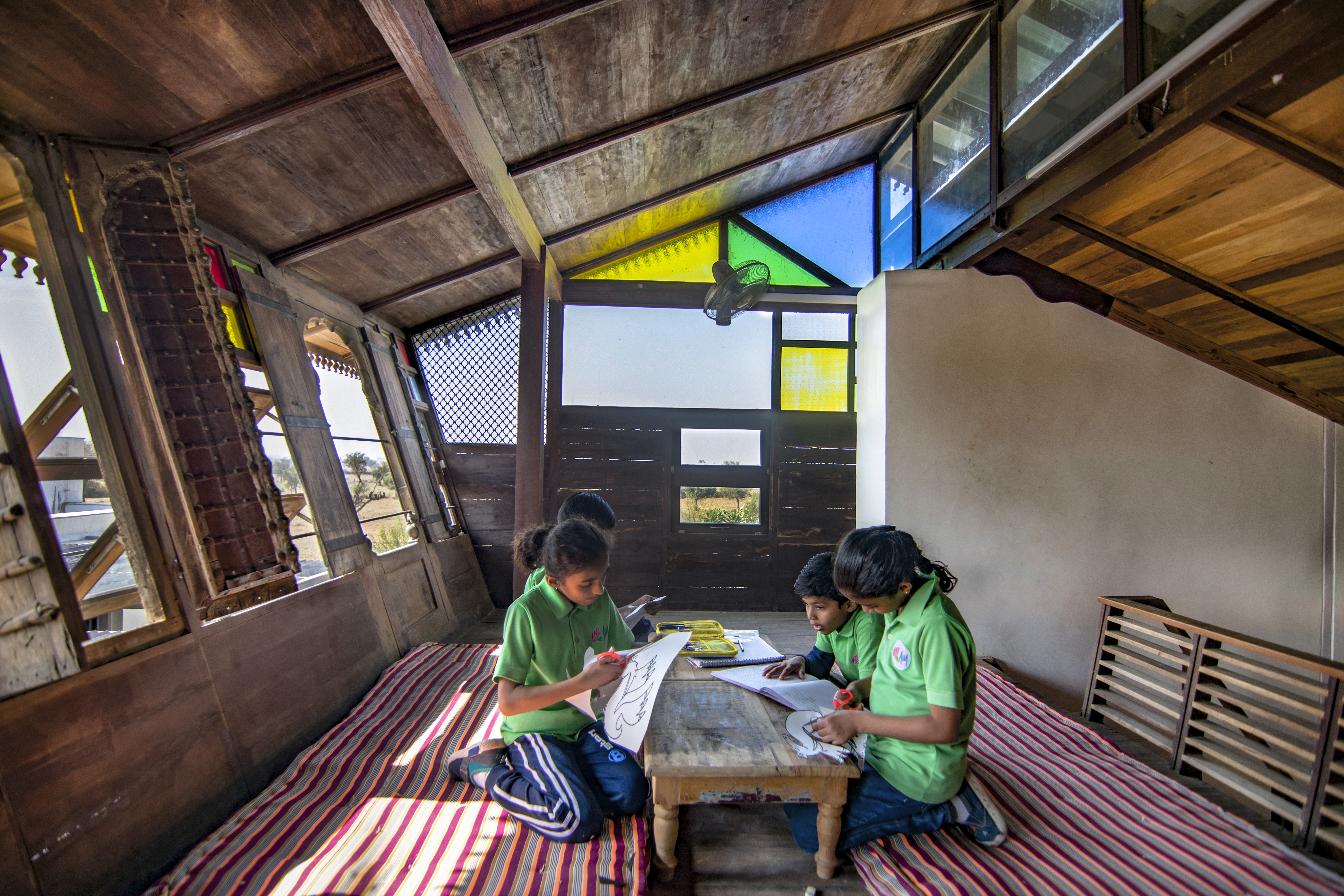 A teacher and two schoolgirls are examining a globe together in a classroom