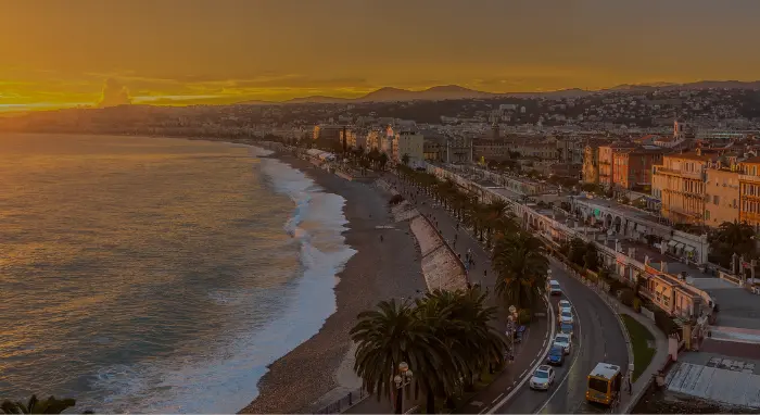 Vue aérienne de Nice au coucher du soleil, mettant en valeur le littoral, la marina et la Méditerranée.